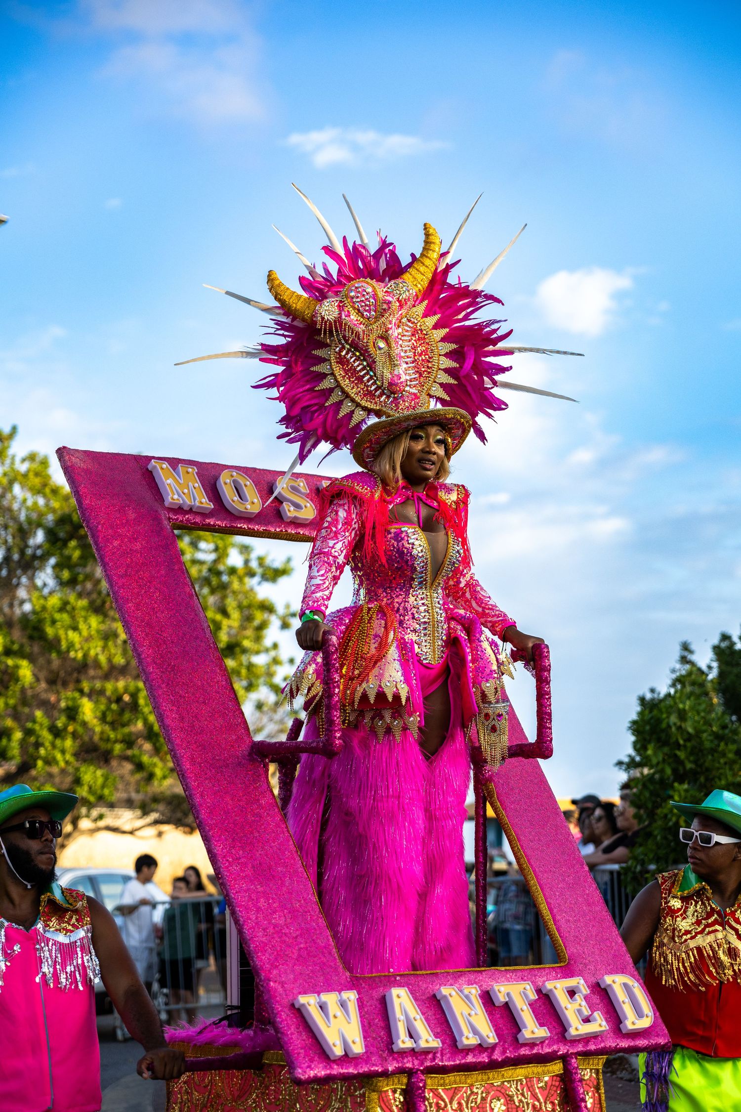 Large pink carnival display with 'WANTED' text and performers in elaborate feathered costumes.