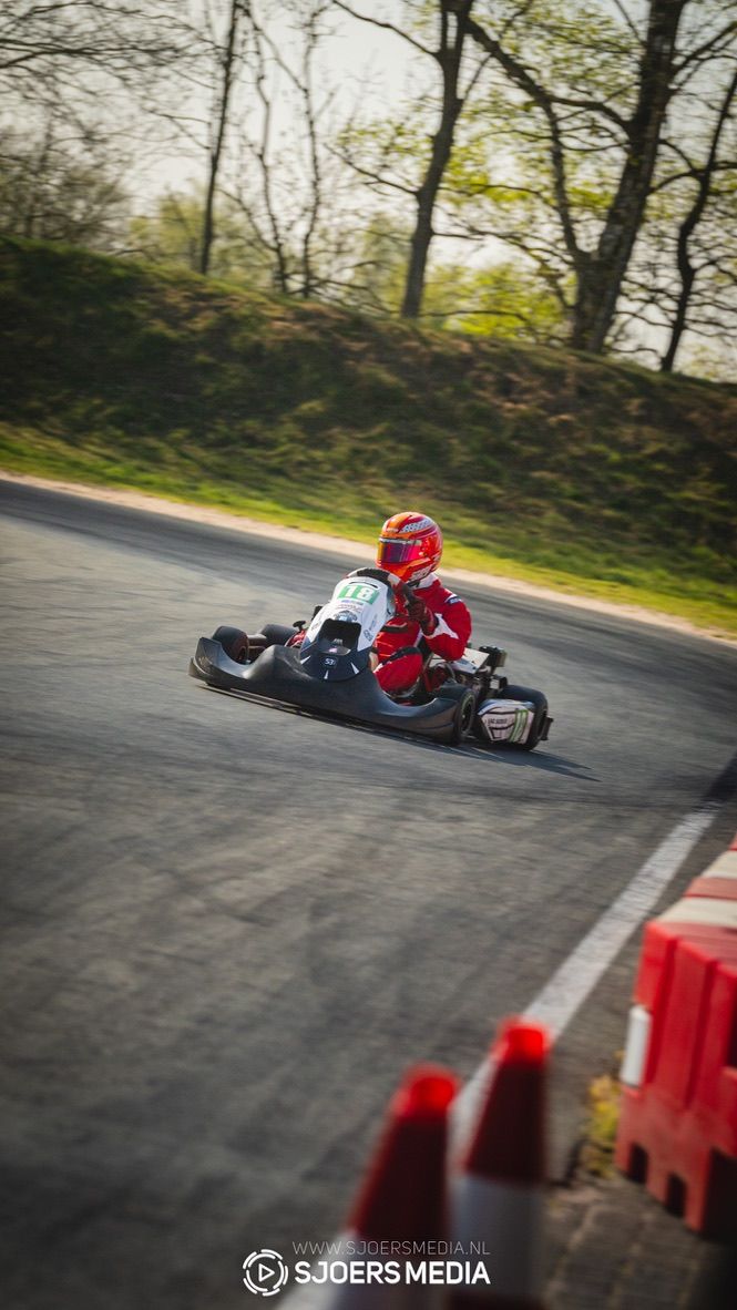 Go-kart racer navigates a corner at speed on an asphalt track.