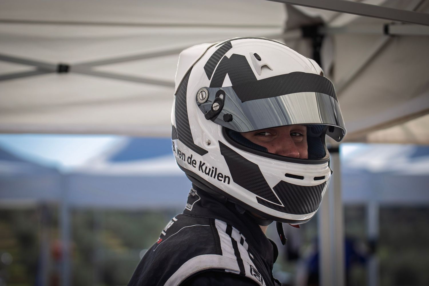 Row of white racing helmets lined up at an outdoor karting event.