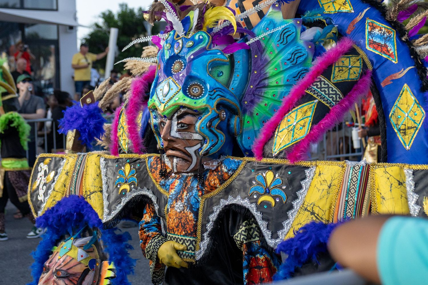 Ornate carnival mask with vibrant blue and yellow feathers displayed during festival performance.