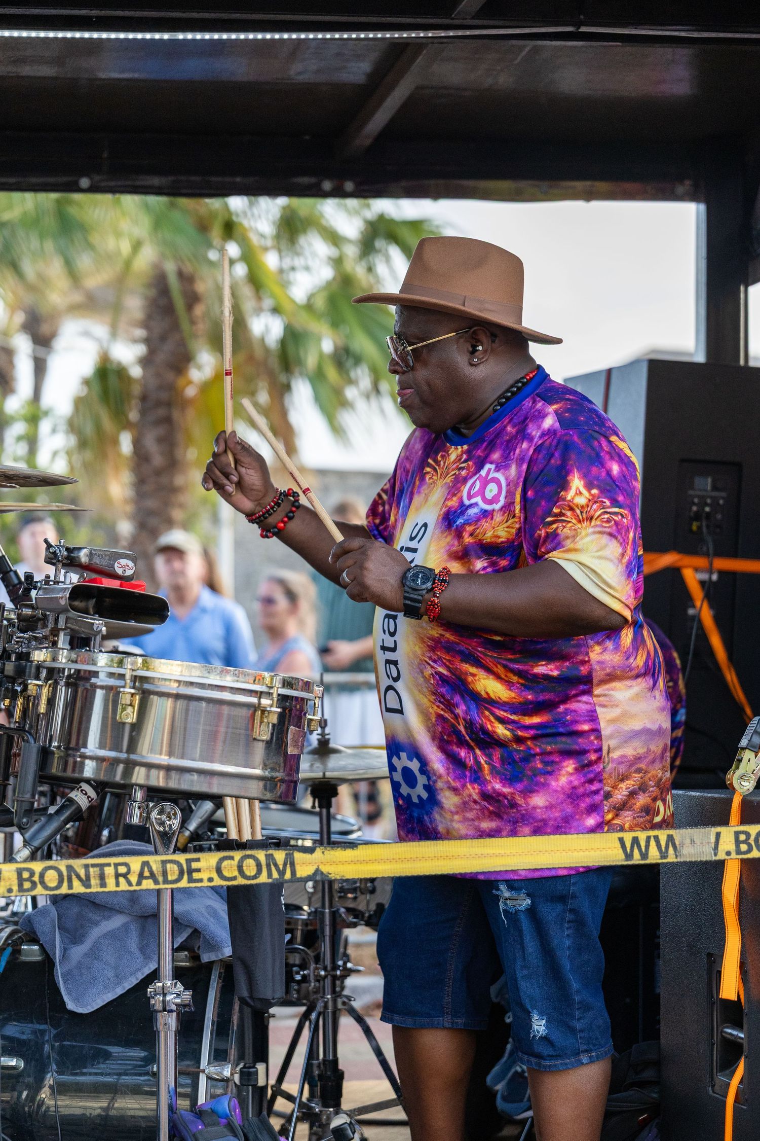 Musician performing with drums and percussion equipment at outdoor festival.