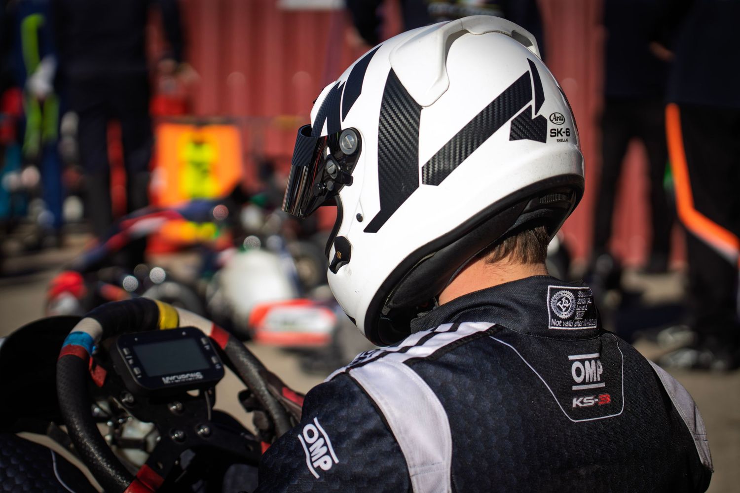 Close-up of white racing helmet with black accents worn by go-kart driver.