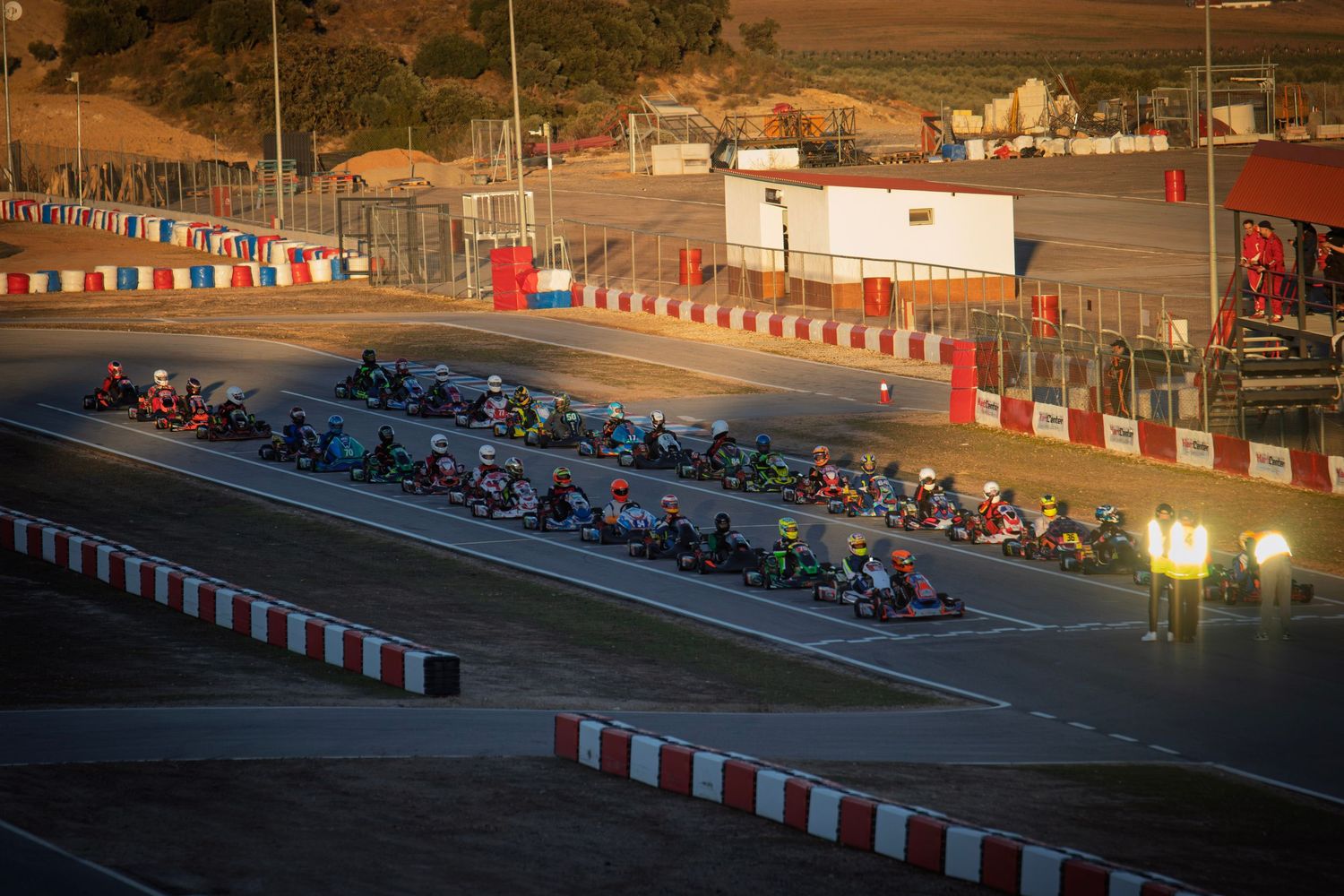 Line of go-karts at starting grid during golden hour at outdoor racing circuit.