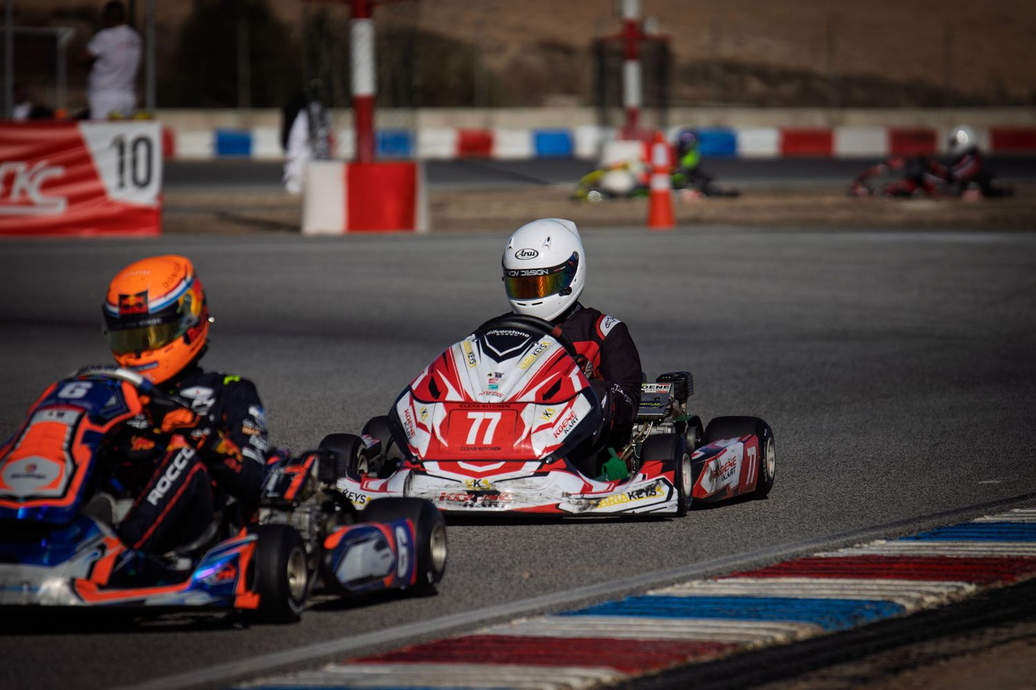 Racing go-karts battling for position through a technical section of the track.