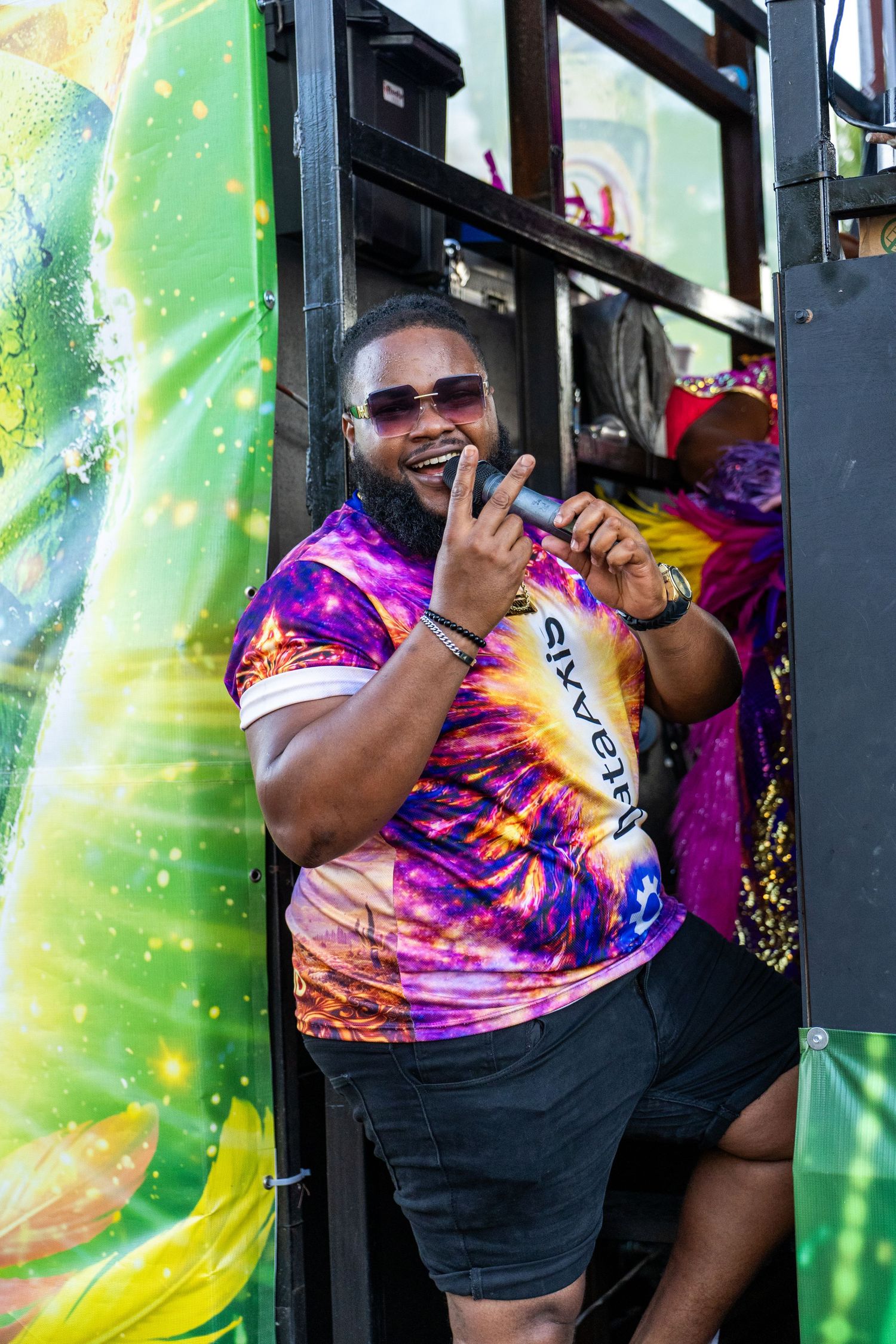 Performer in tie-dye shirt entertaining crowd at outdoor festival.