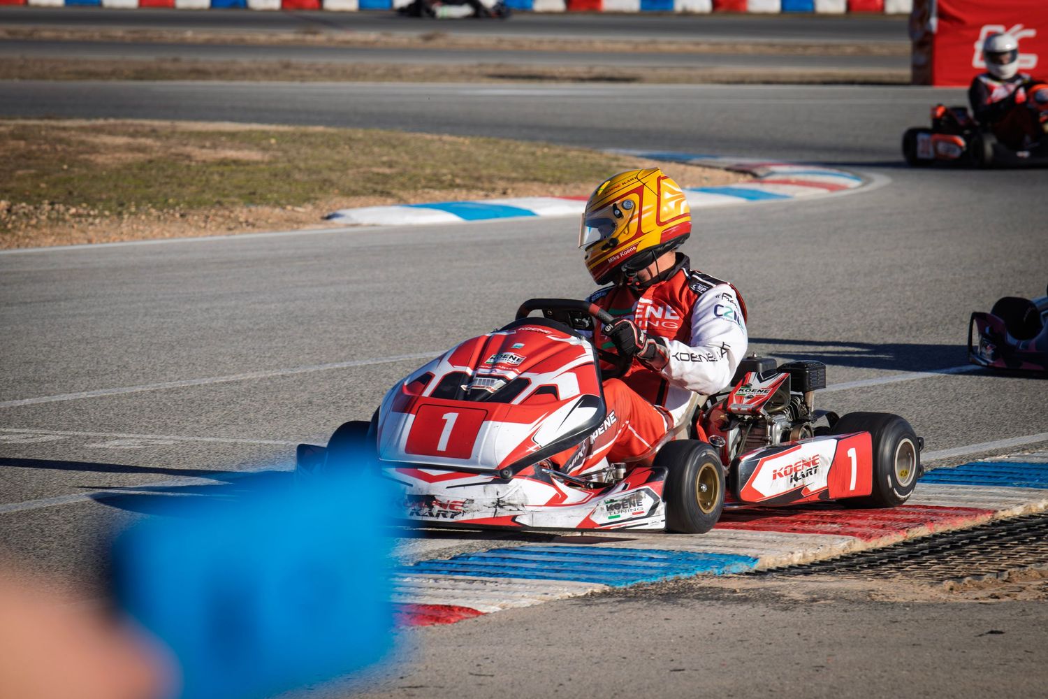 Go-karts racing through a challenging corner section with distinctive track markings visible.