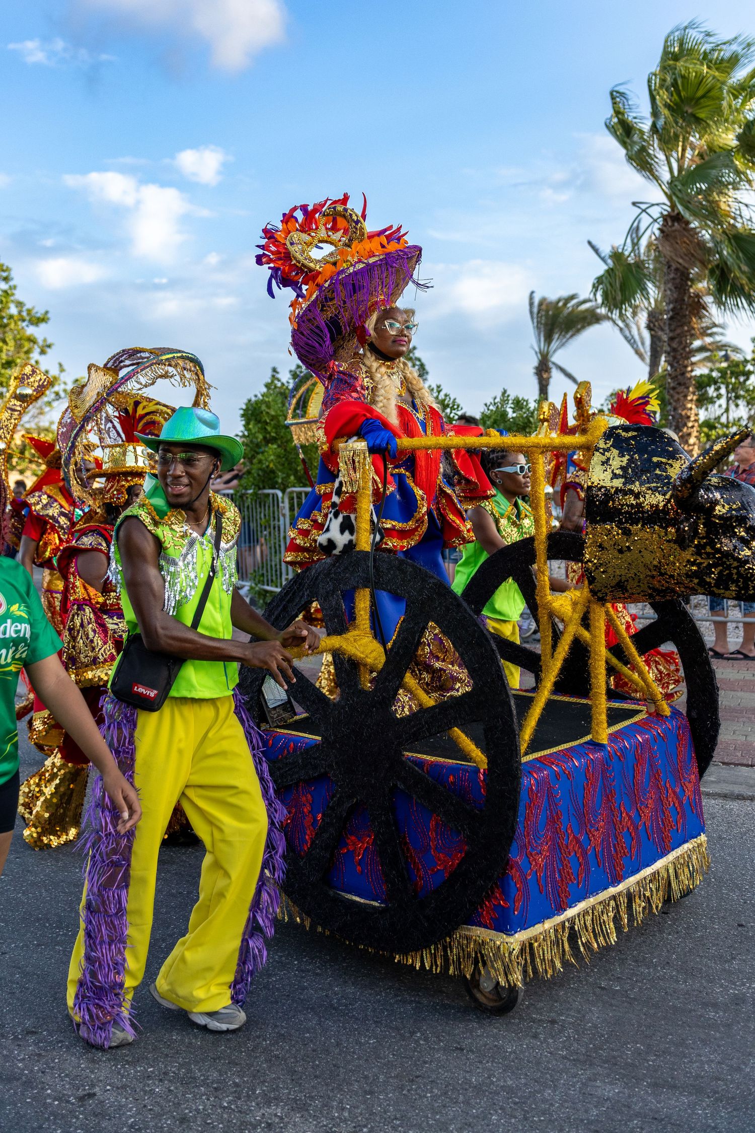 Colorful carnival parade float with vibrant decorations and performers in bright costumes dancing in the street.