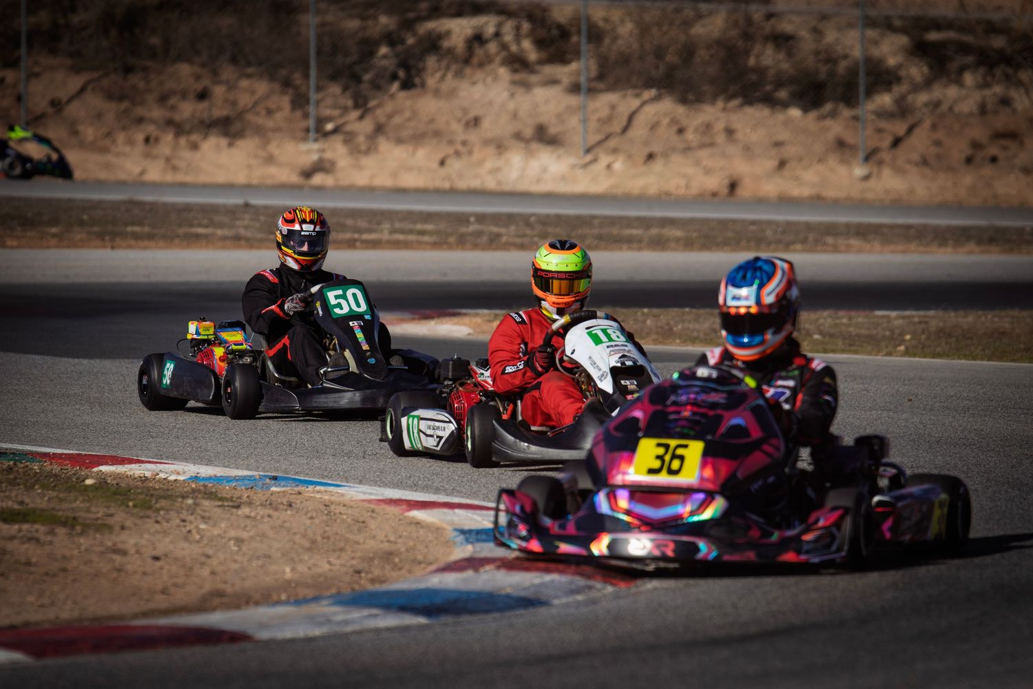 Go-karts competing on a winding race circuit with colorful track markings visible.