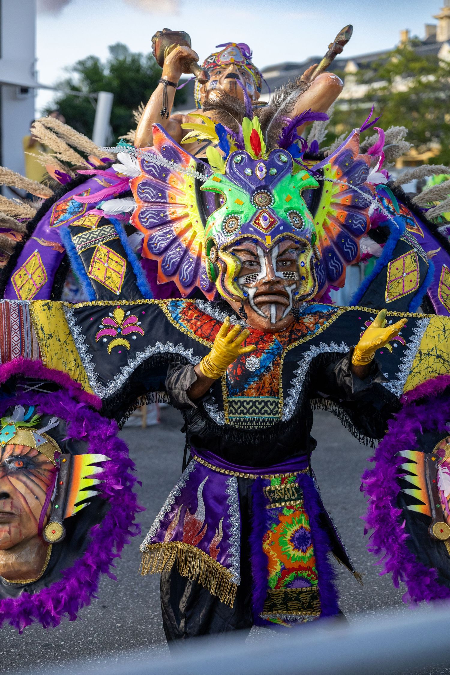 Dancer wearing elaborate colorful mask and feathered carnival costume performs at festival.