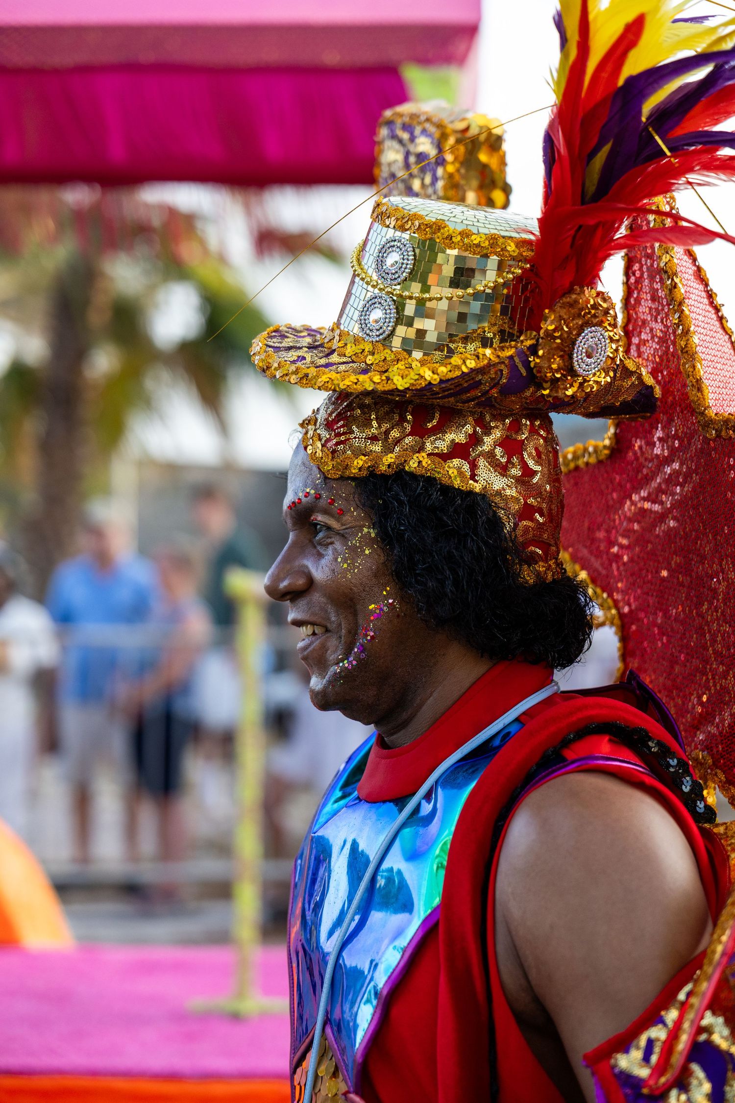Performers in red costumes and gold headdresses smiling during carnival celebration.