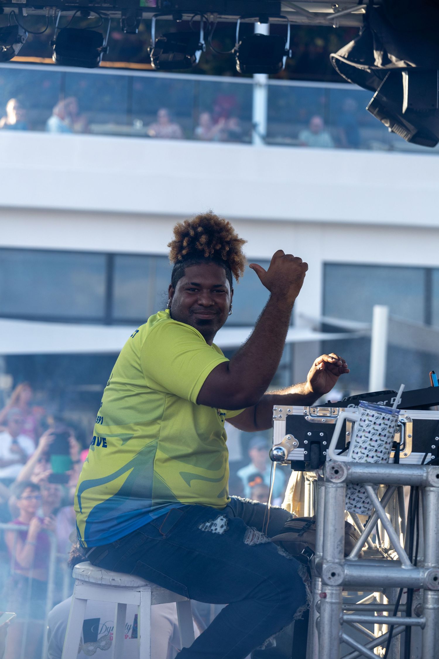 DJ in neon yellow shirt performing at outdoor event.