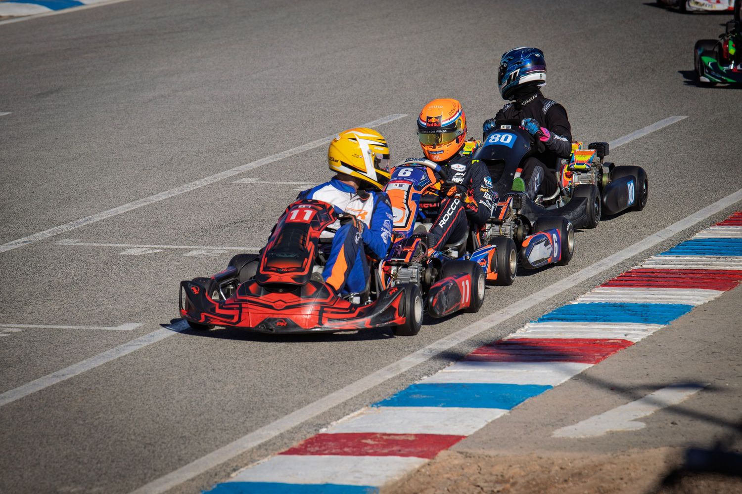 Go-karts racing through a technical chicane with red, white and blue curbing.