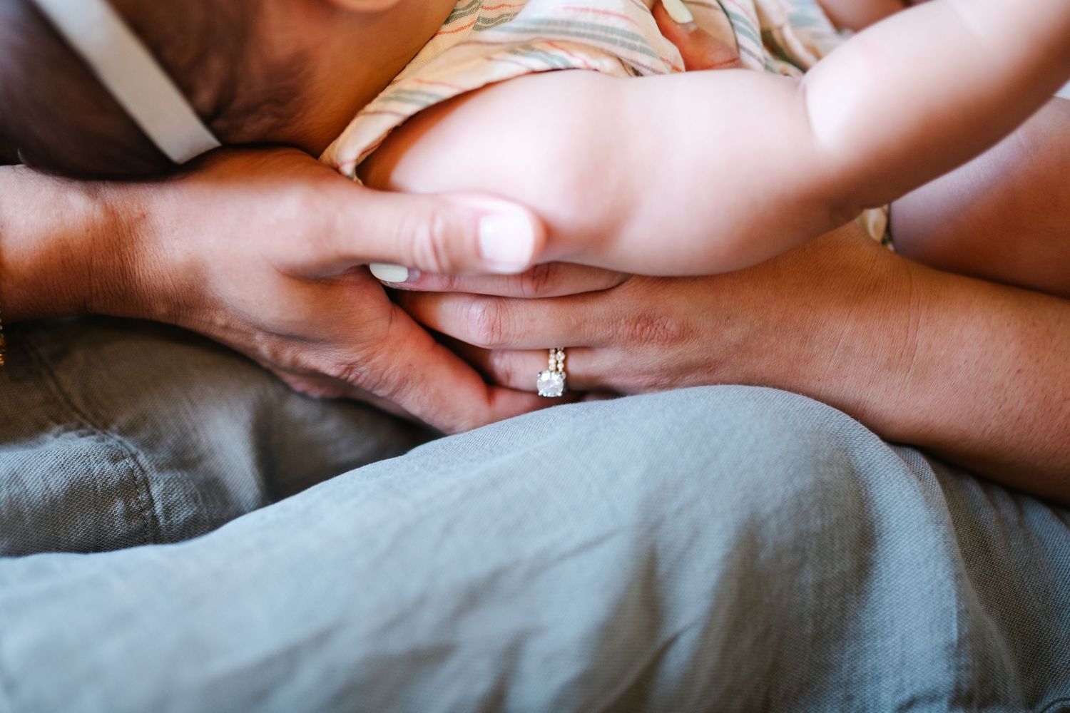 Close-up shots of gentle hands touching and intertwining on a soft gray surface.