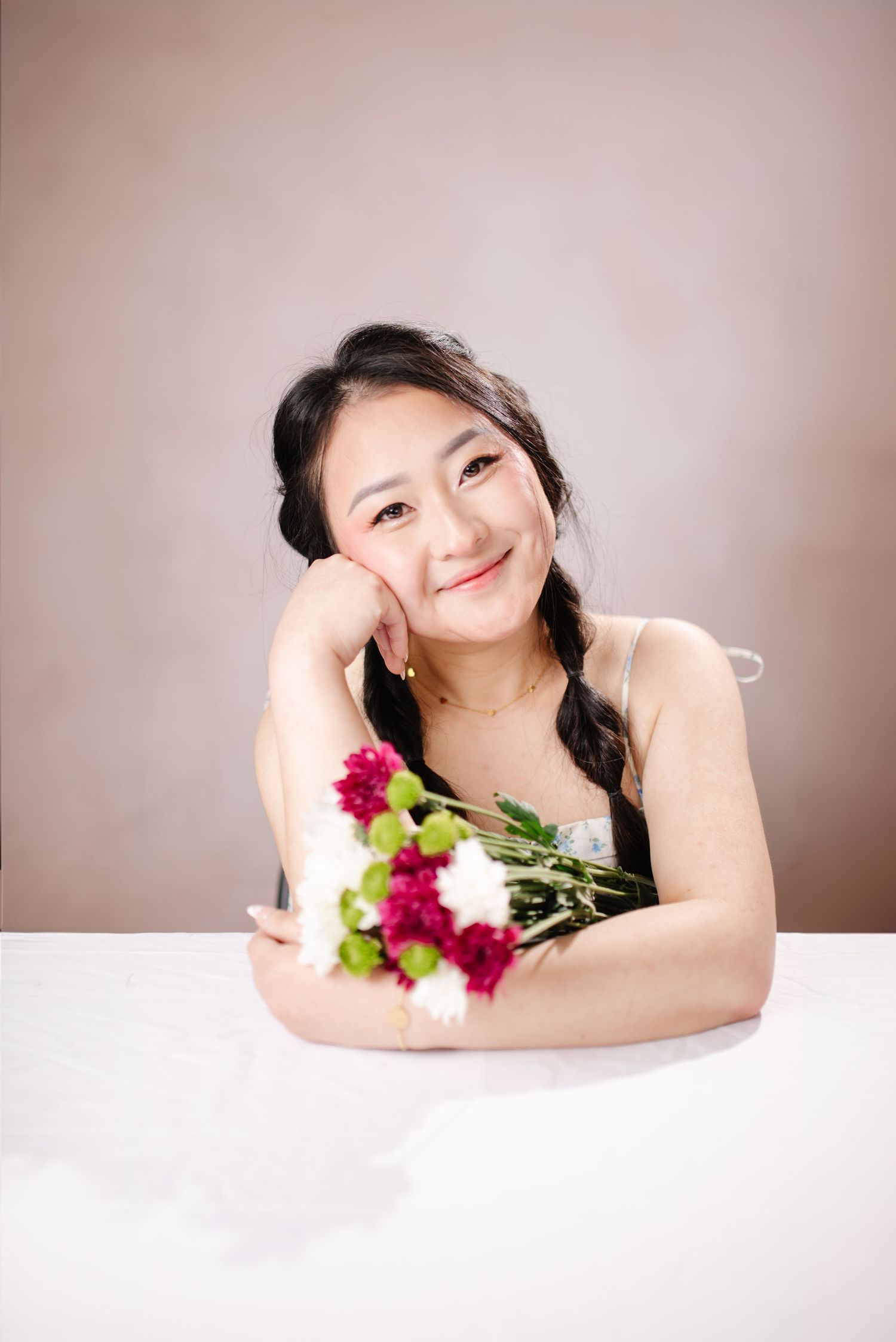 Studio portrait with red flowers against neutral background.
