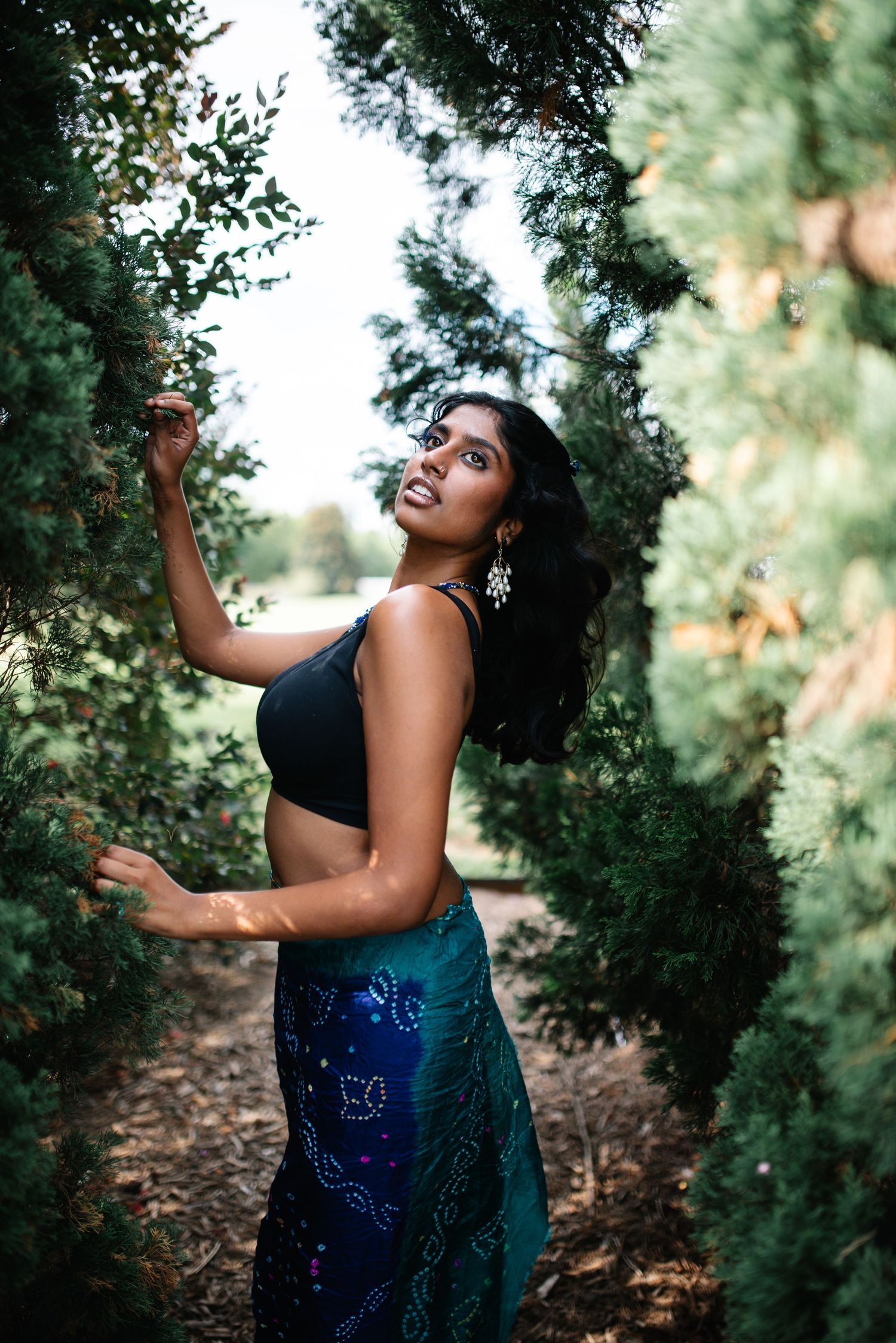Artistic portrait series of woman dancing among green foliage.