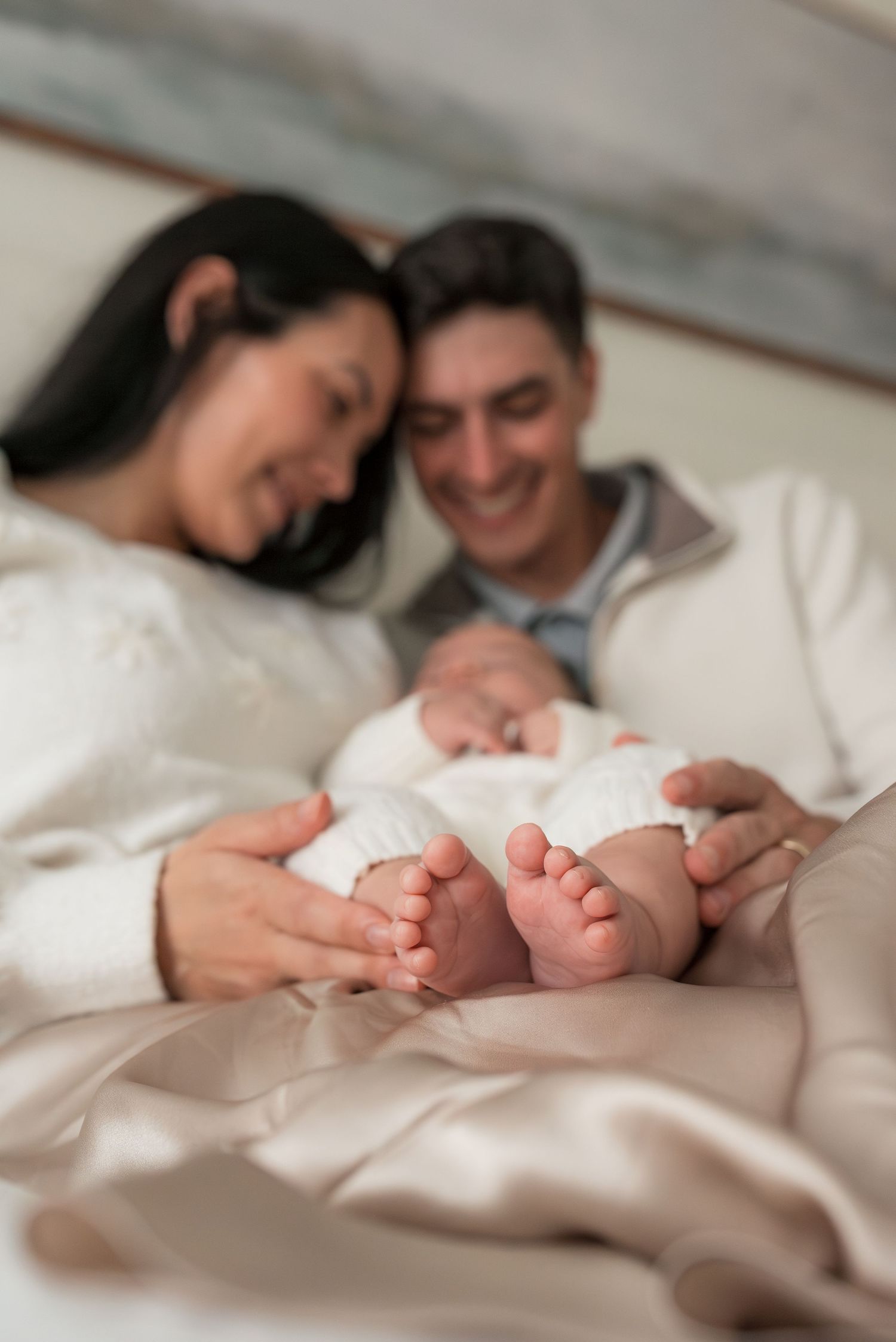 Close-up of tiny baby feet held by parents wearing cozy white sweaters.