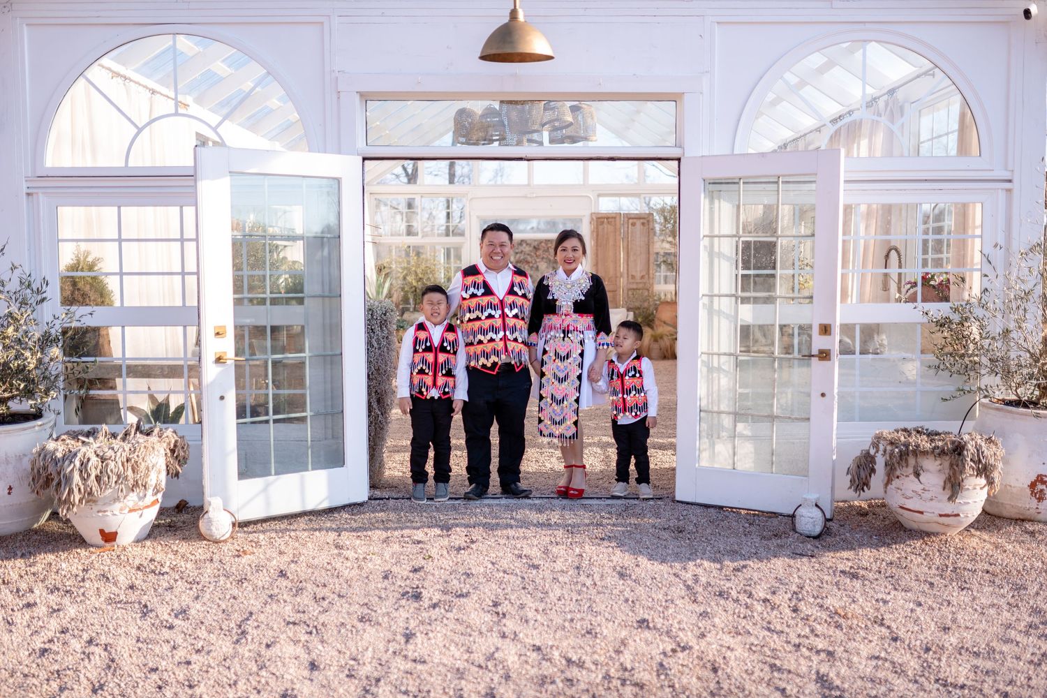 A family poses together in matching holiday sweaters in front of French doors.