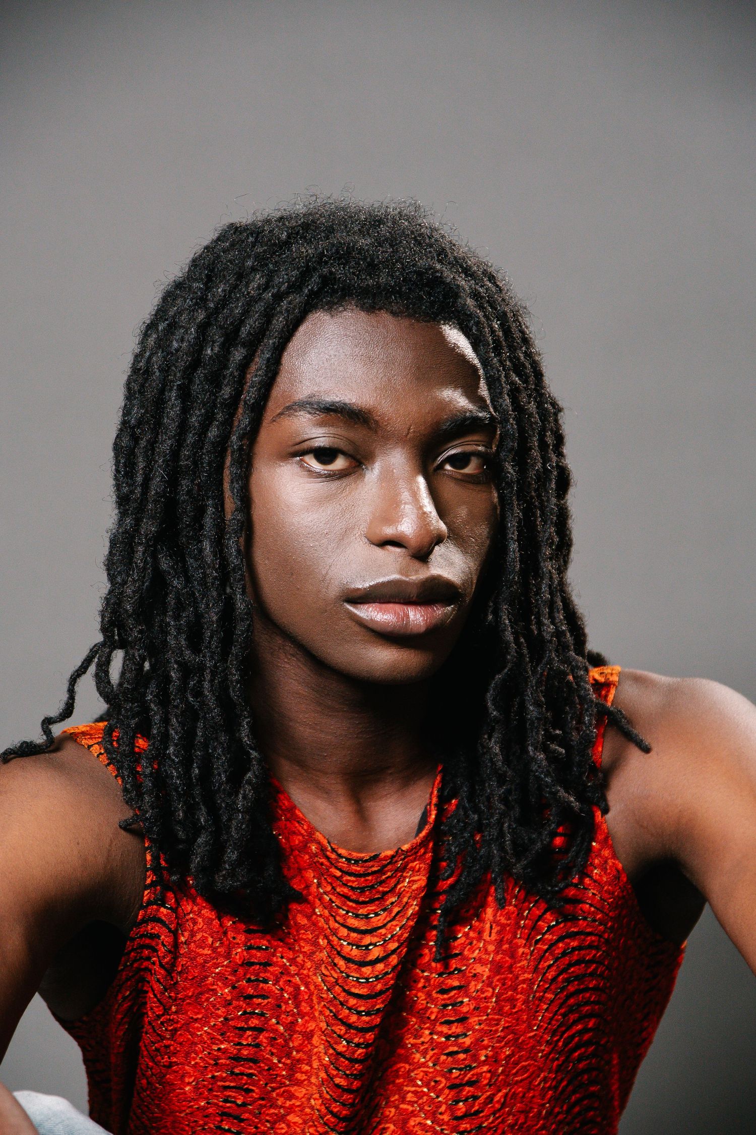 Artistic portrait series in red sequined top against grey studio background.