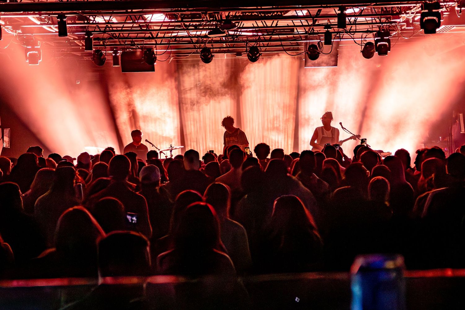 Concert crowd silhouettes against dramatic red stage lighting.