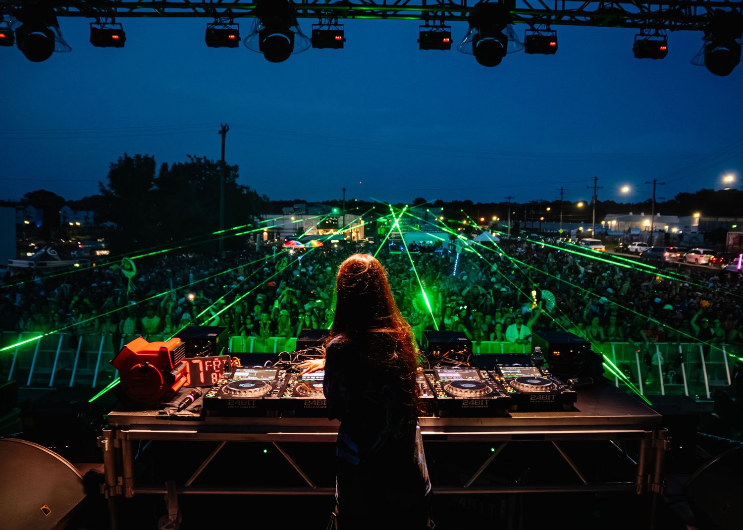 DJ equipment and controllers illuminated at night with colorful lighting.