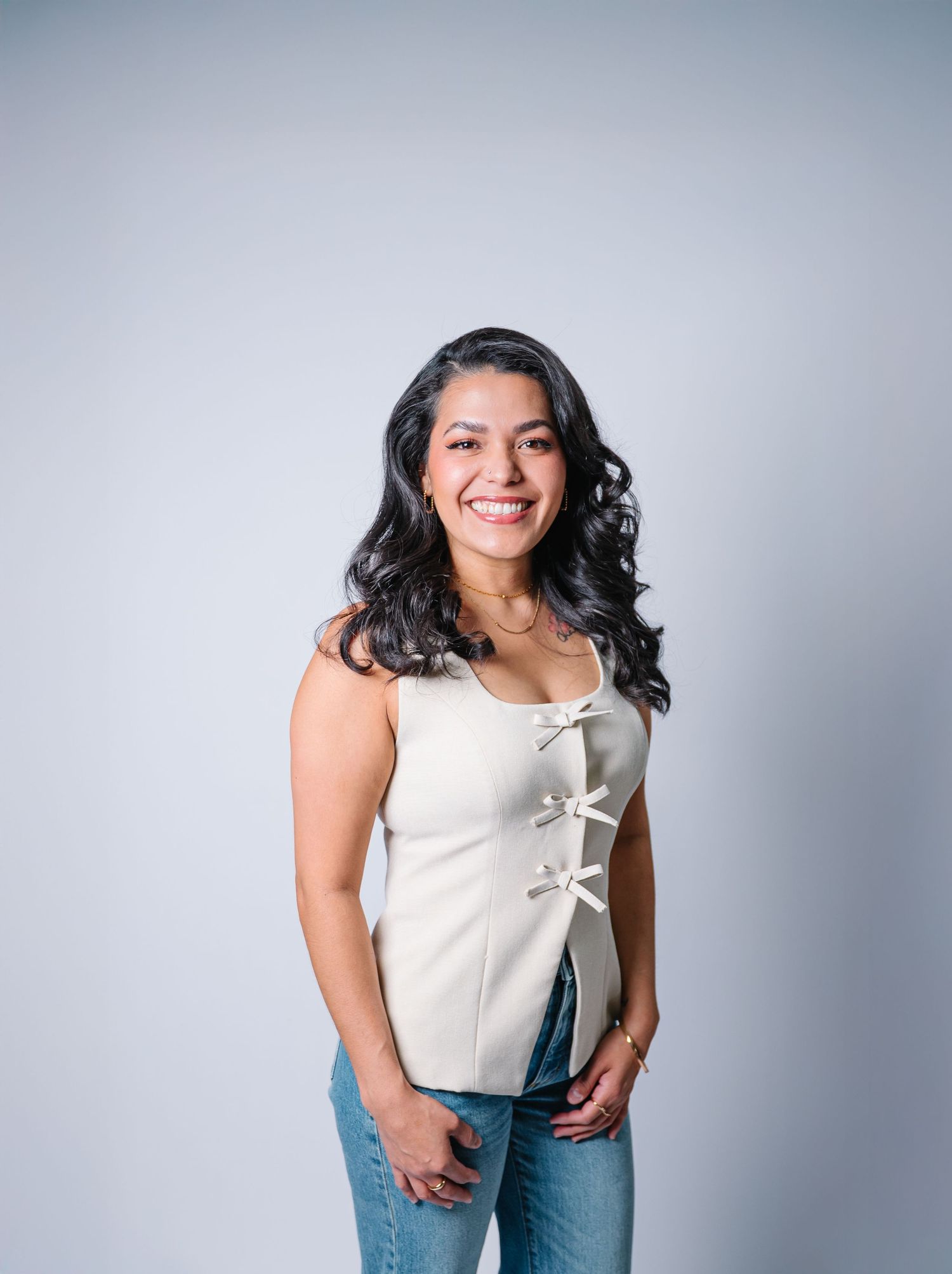 Portrait against grey background wearing white top and blue jeans.