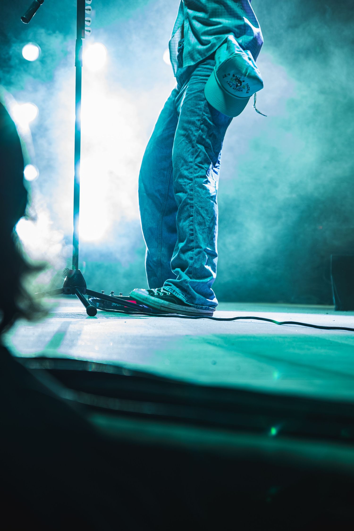 Close-up of performer's feet on stage bathed in teal lighting and smoke effects.