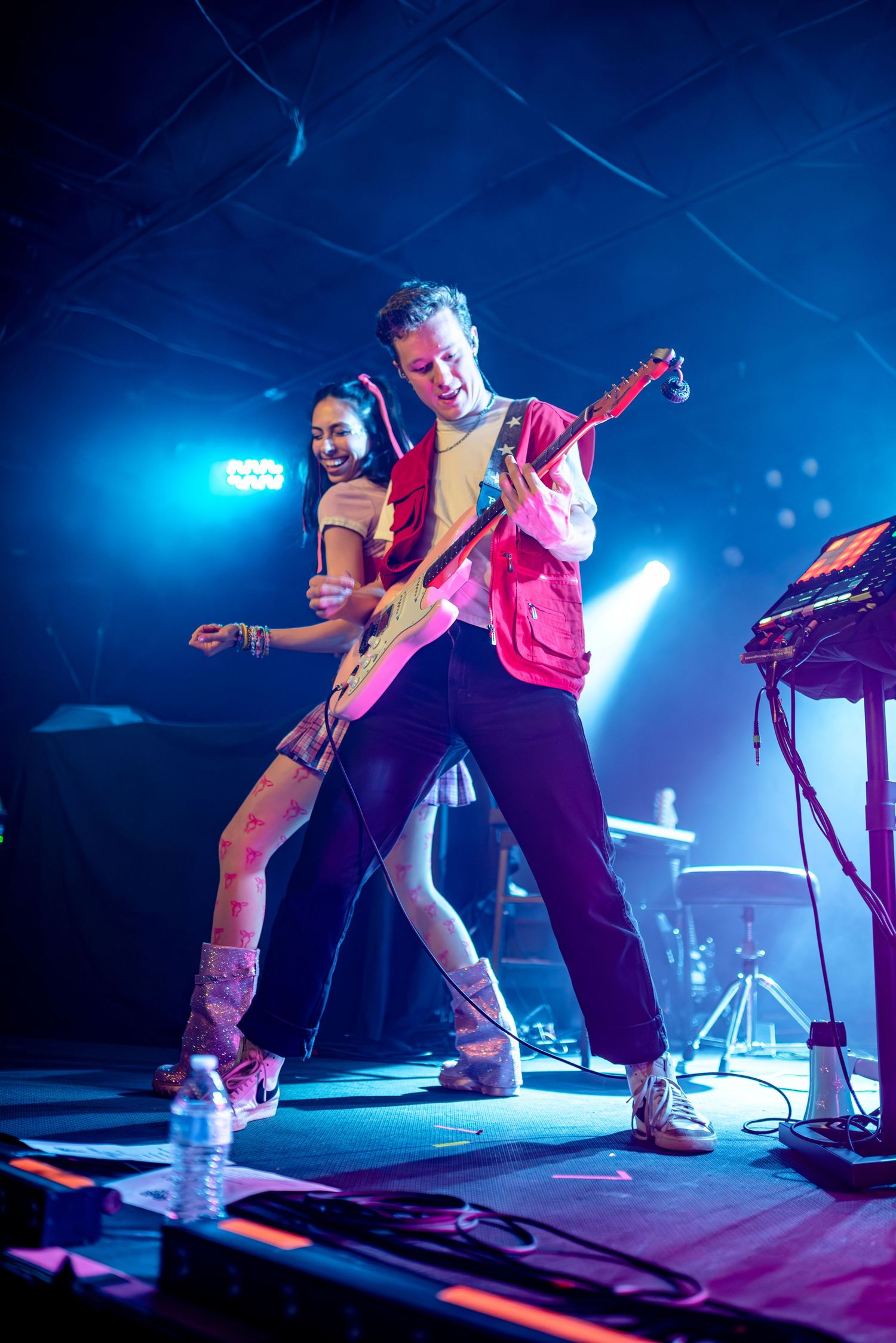 Musicians performing energetically on stage with vibrant blue lighting effects.