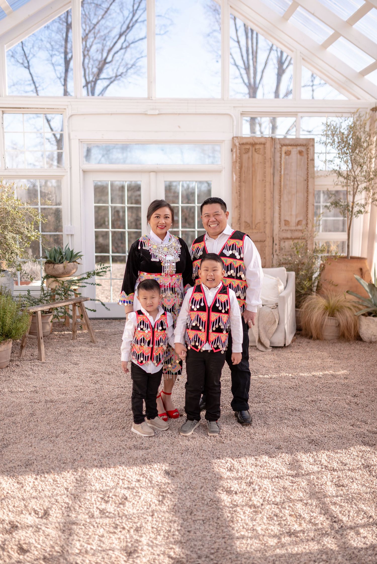 Children in matching red and black sweaters playing in a bright greenhouse setting.
