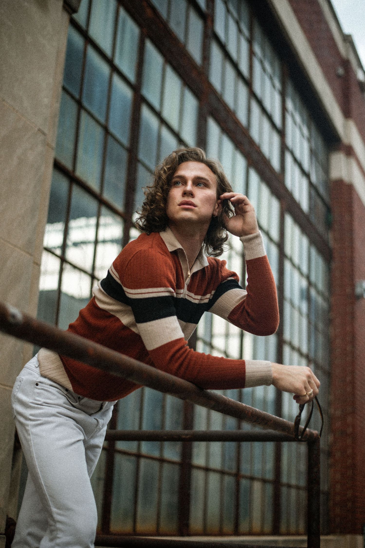 Dynamic dance poses captured against industrial windows and brick wall.