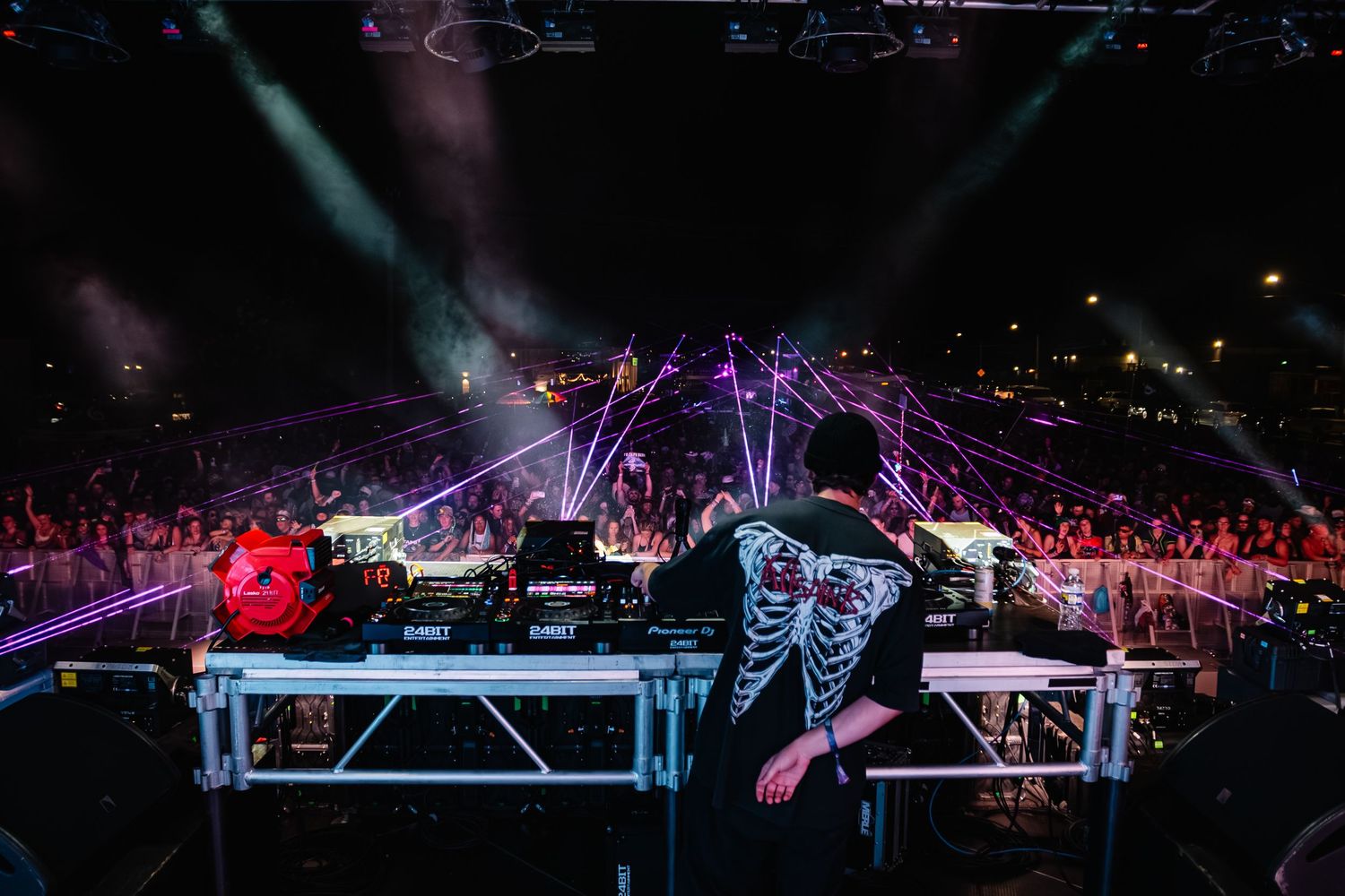 Concert stage setup with lighting rigs and equipment silhouetted against dark background.