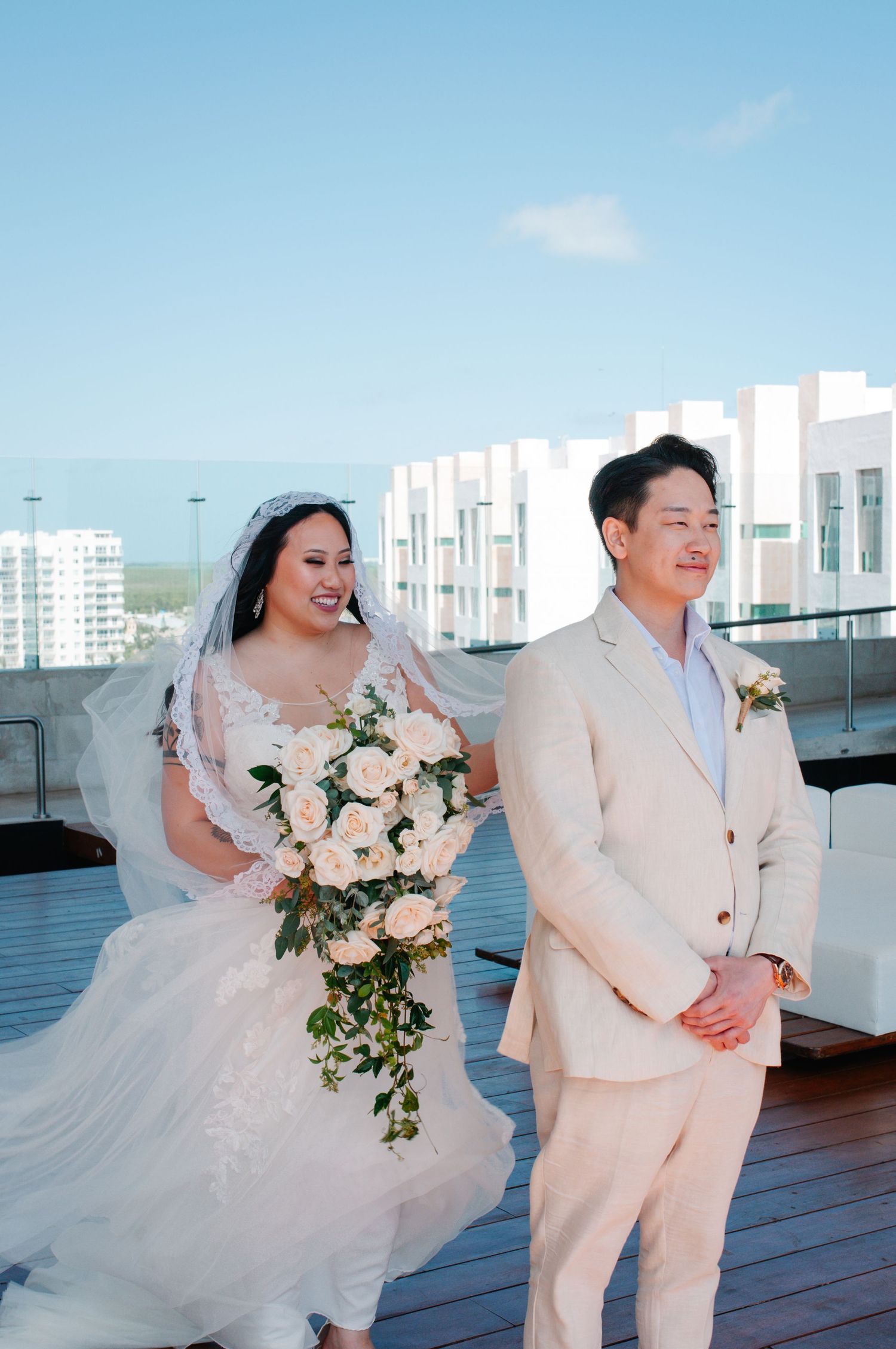 A couple shares a joyful moment on a rooftop terrace during their wedding day.