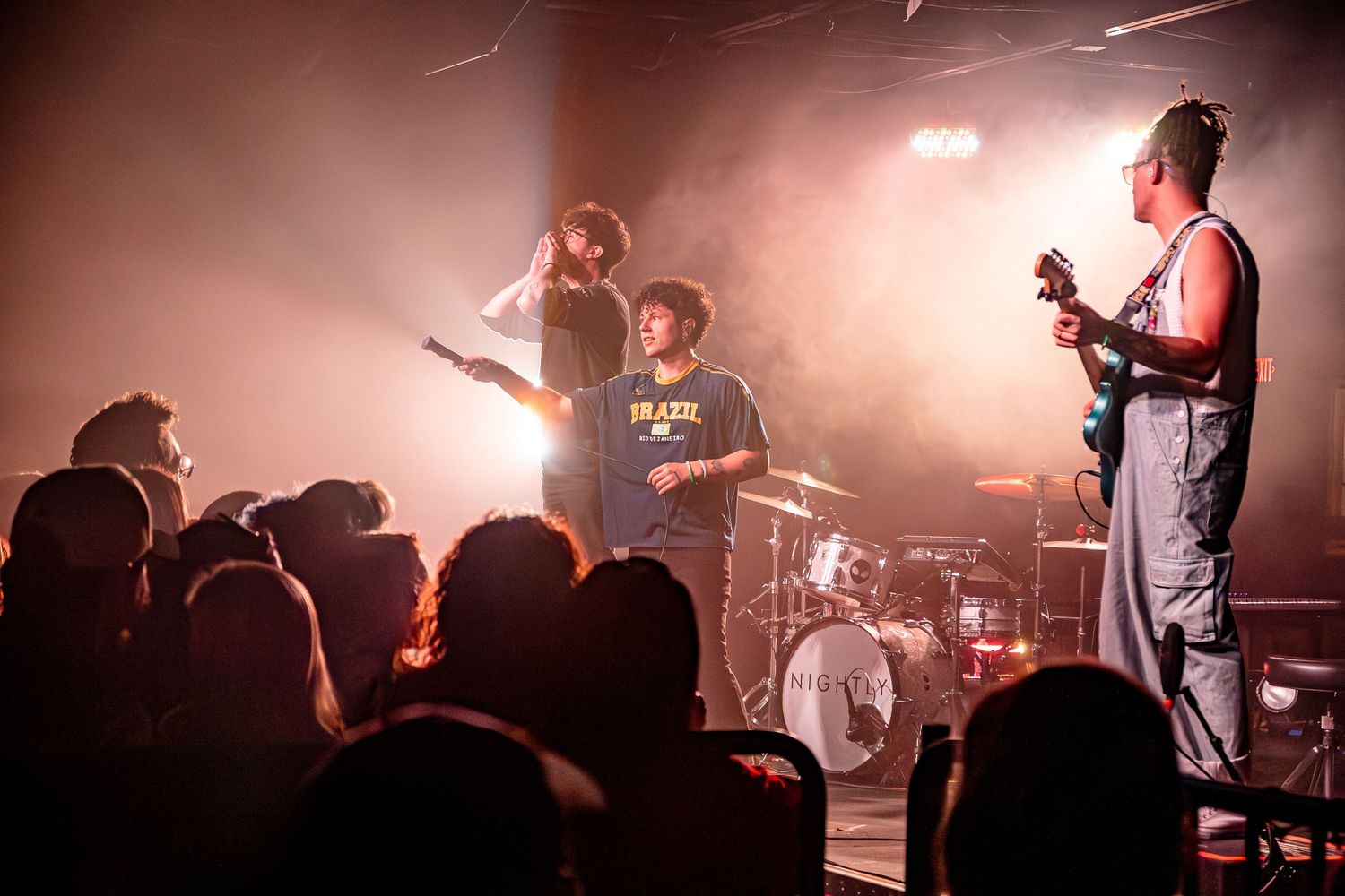 Band performing on stage with red atmospheric lighting and smoke effects.