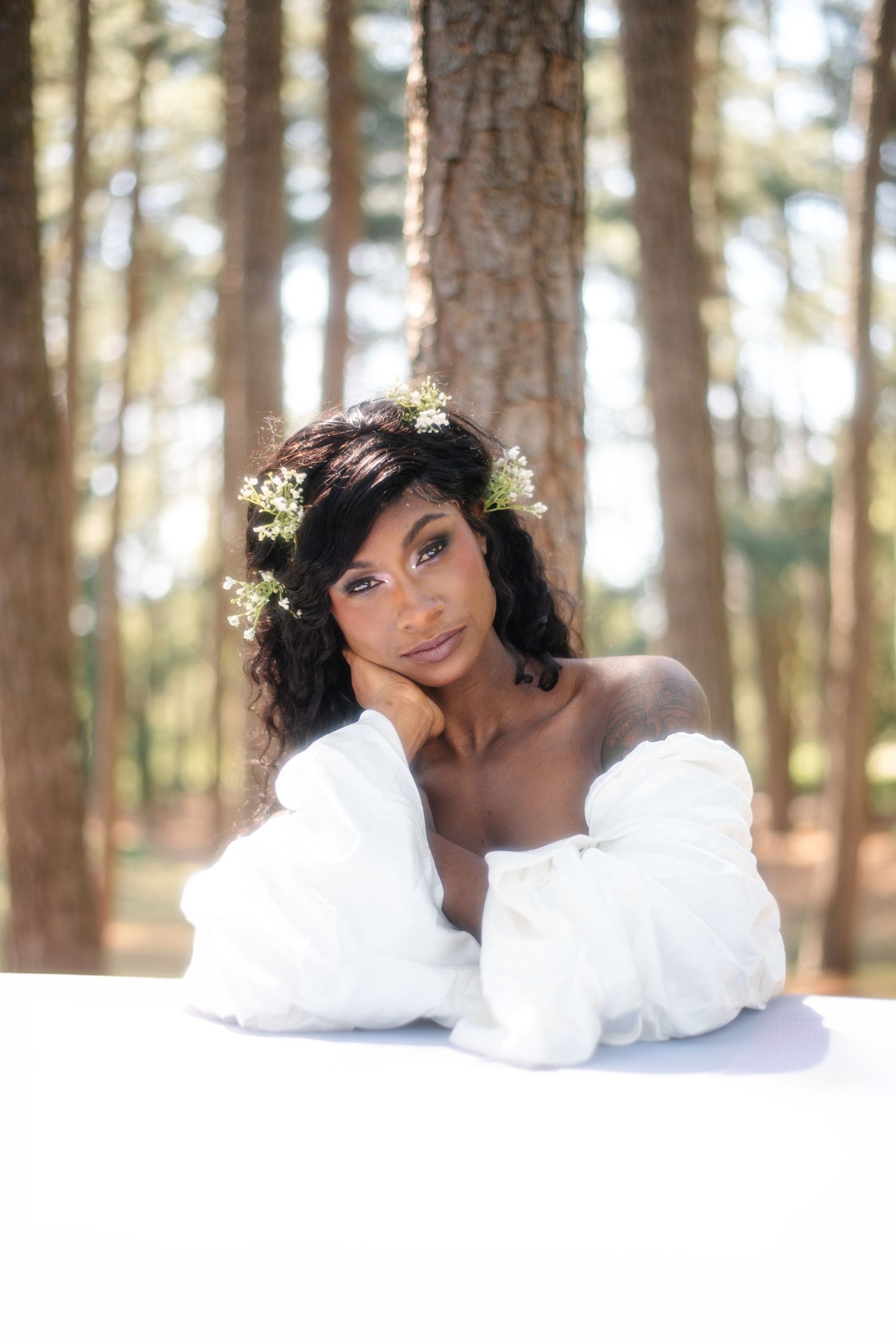 Ethereal portrait in forest setting with white dress and floral crown.