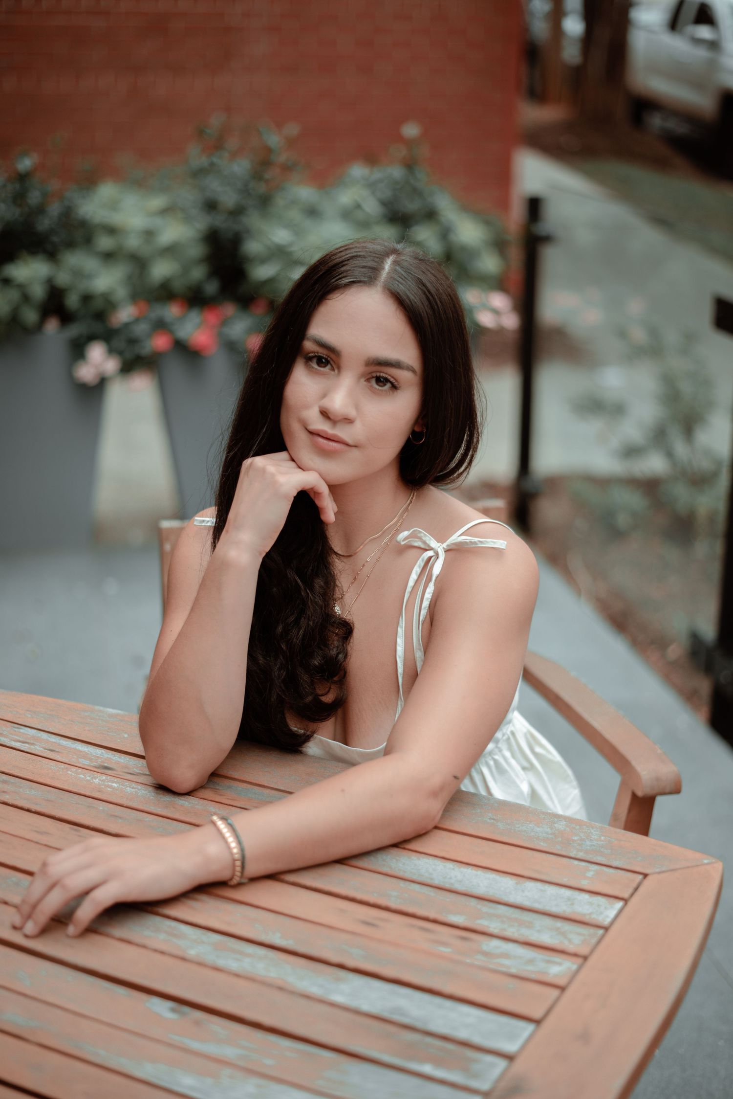 Portrait series of woman in white top resting on wooden table outdoors.