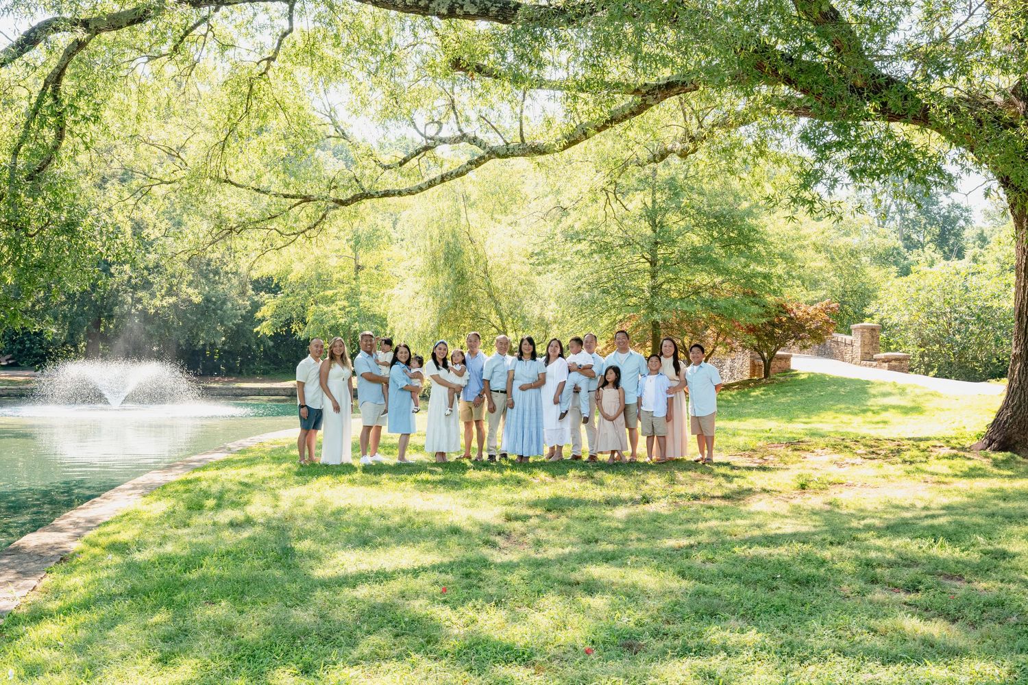Group photo session taking place in a scenic park with fountain and trees.