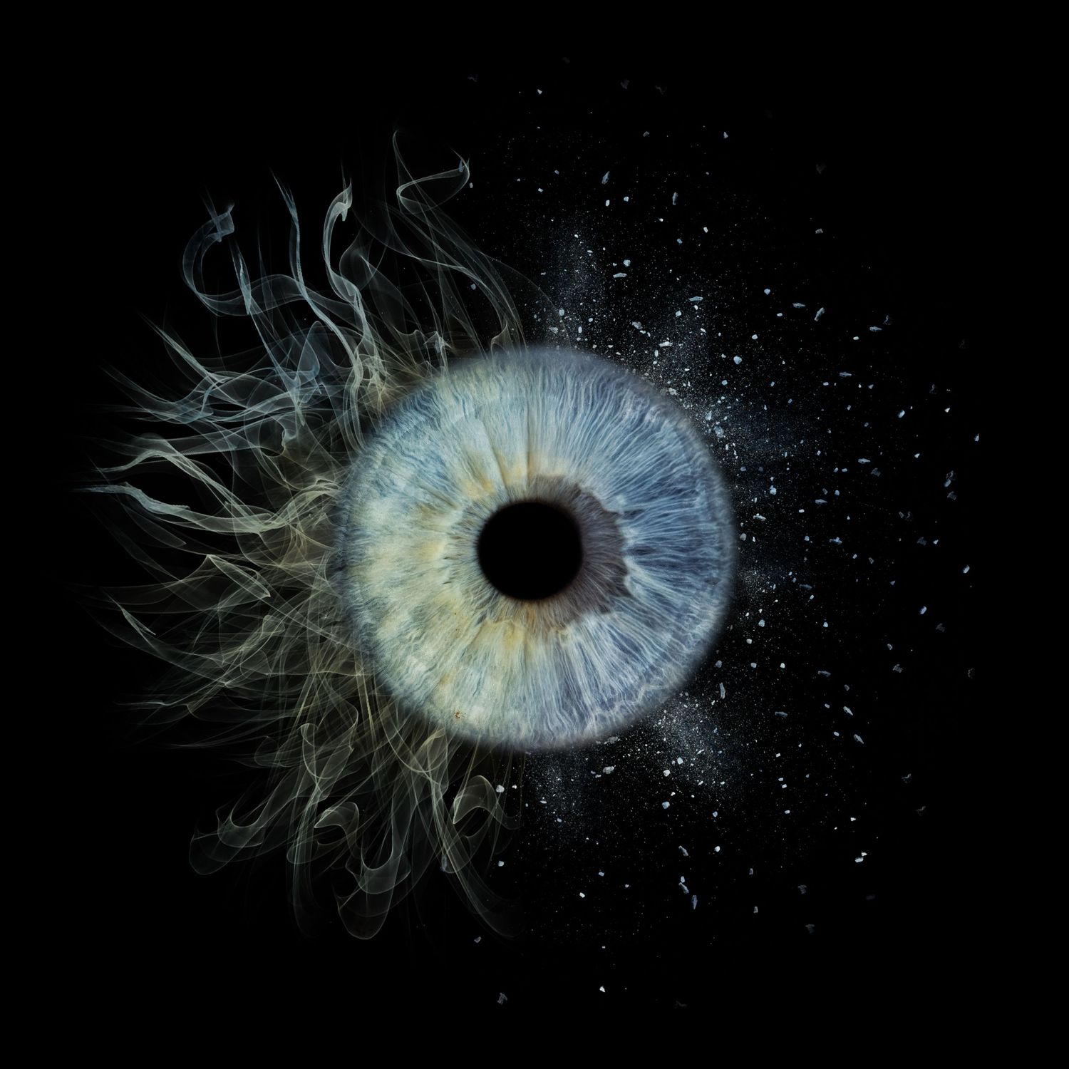 A surreal blue human eye dissolving into wispy smoke and particles against a black background.