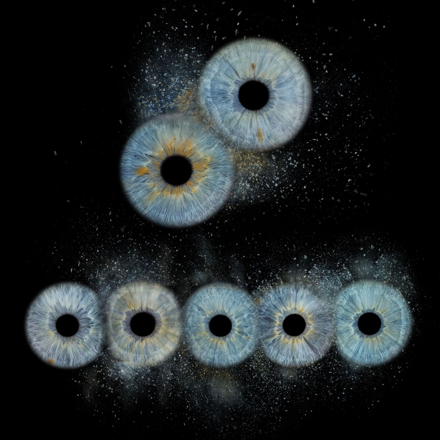 Six blue human irises arranged in a triangle pattern against a dark background with scattered light particles.