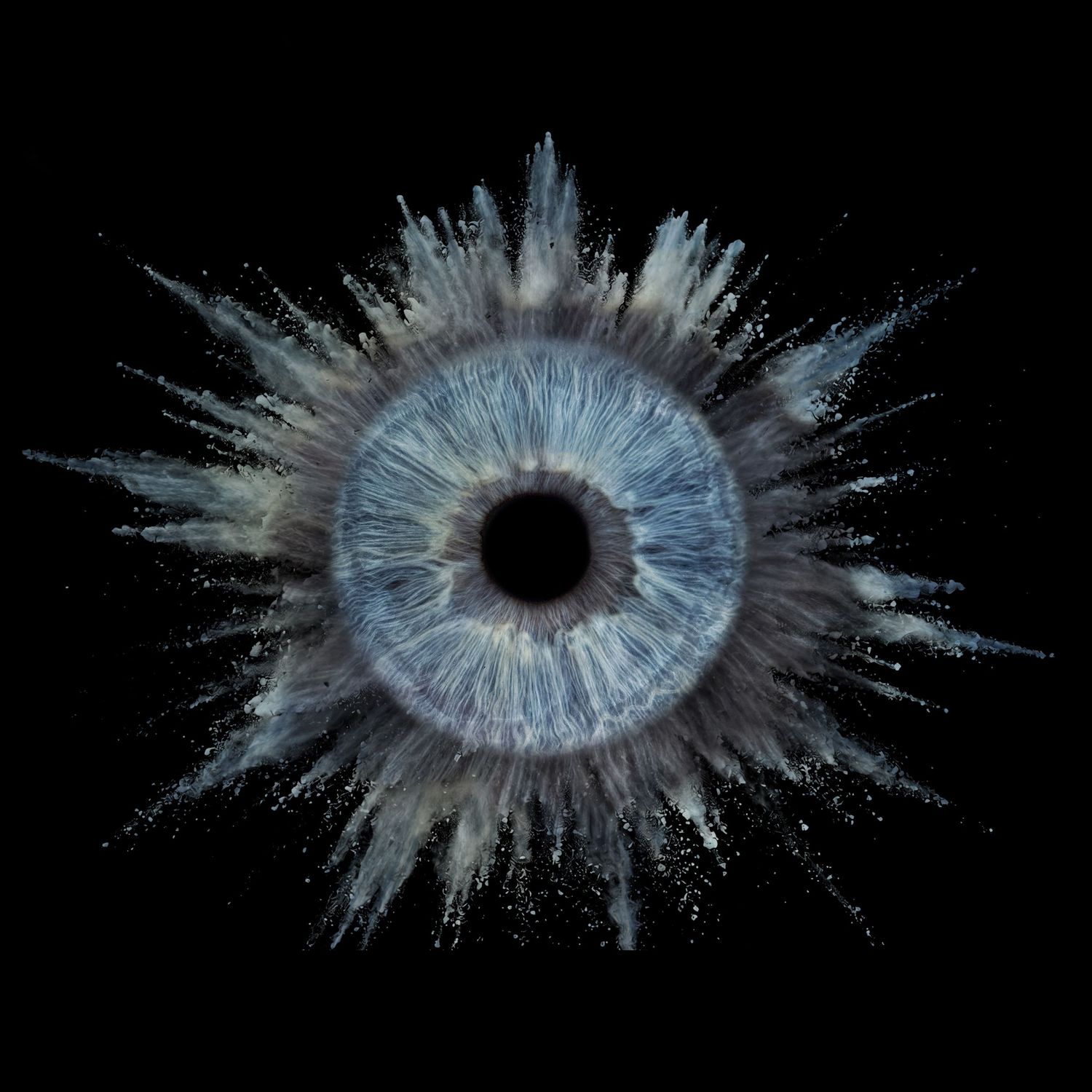 A blue human iris exploding outward with dust and particles on a black background.