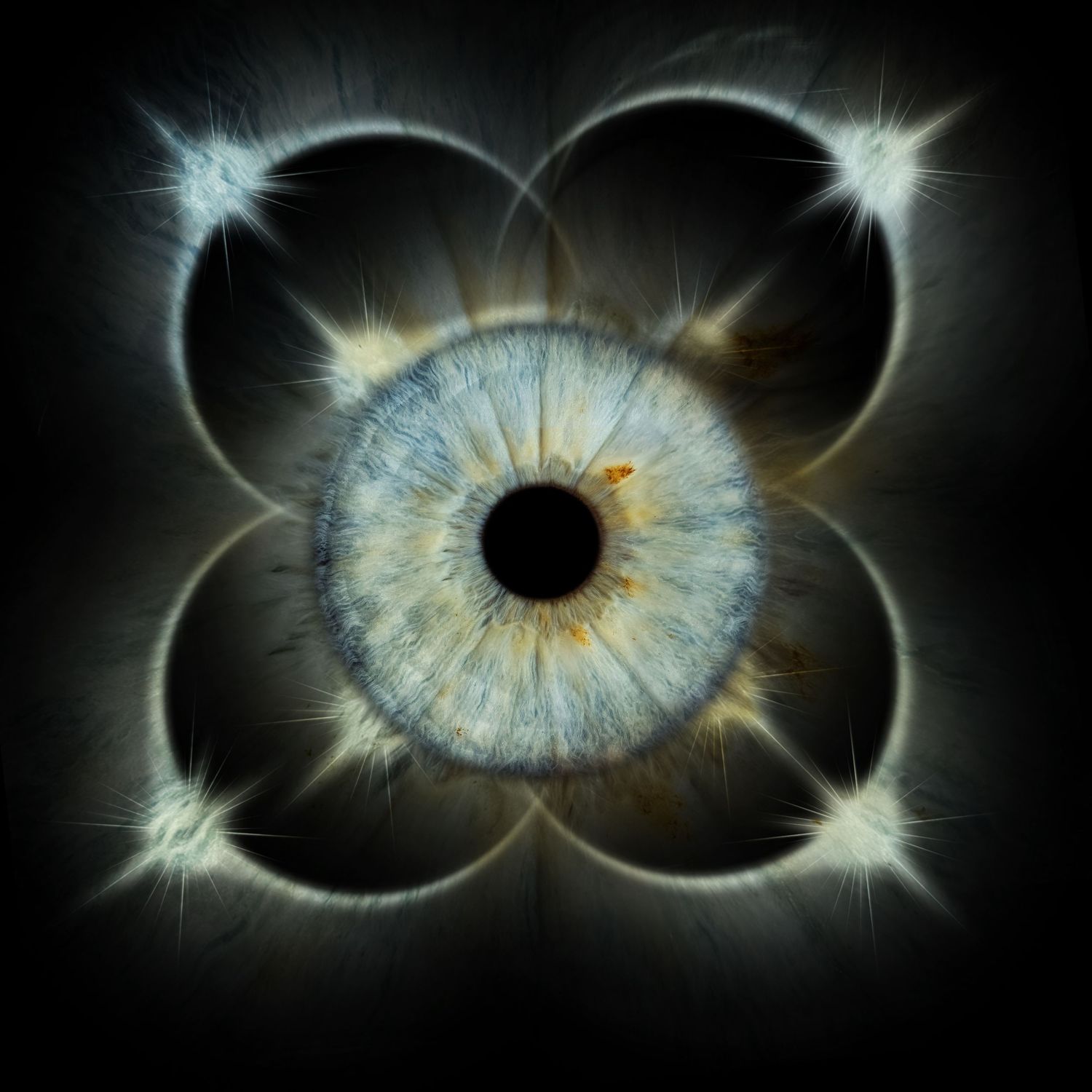 A surreal human eye with blue iris centered in a four-petal flower geometric pattern with glowing light bursts on black background.