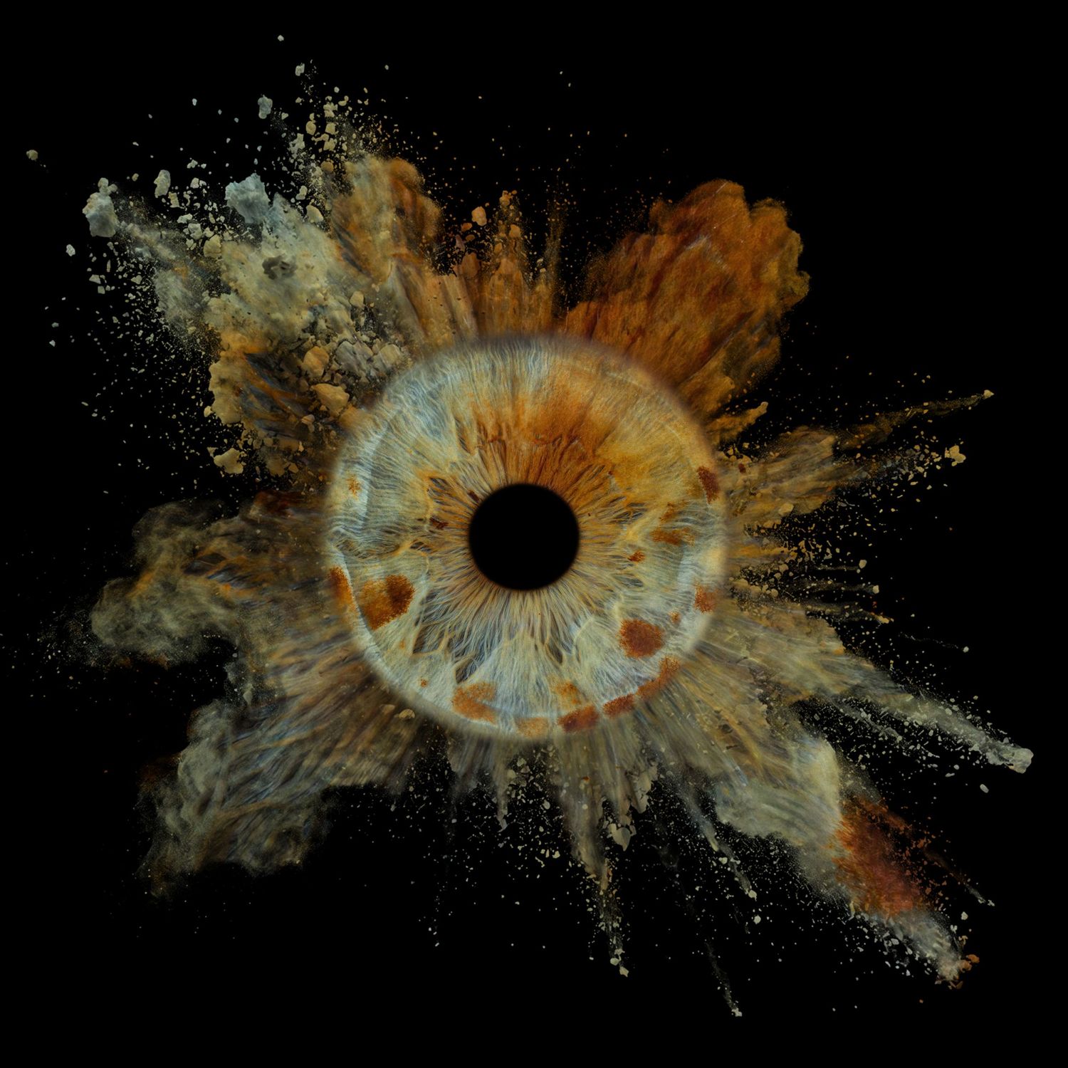 Macro human iris photography with dramatic amber powder explosion burst on black background.