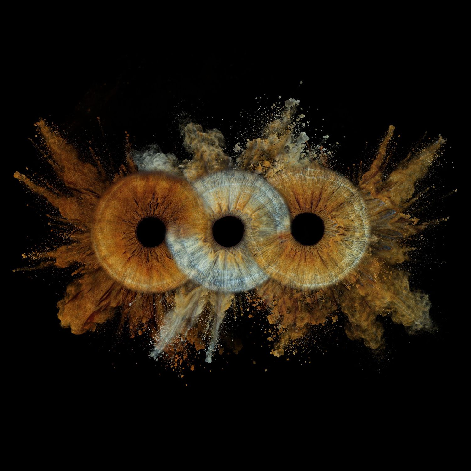 Three amber eyes with explosive powder bursts on black background, creating surreal artistic composition.
