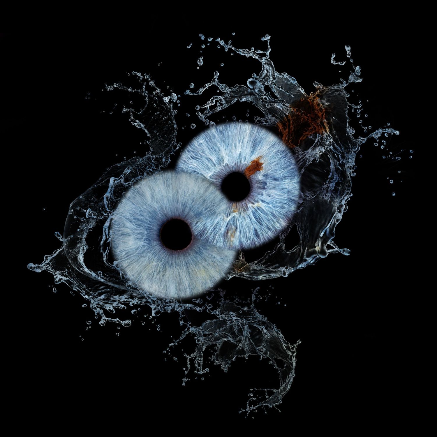 Two blue human irises surrounded by dramatic water splash on dark black background.