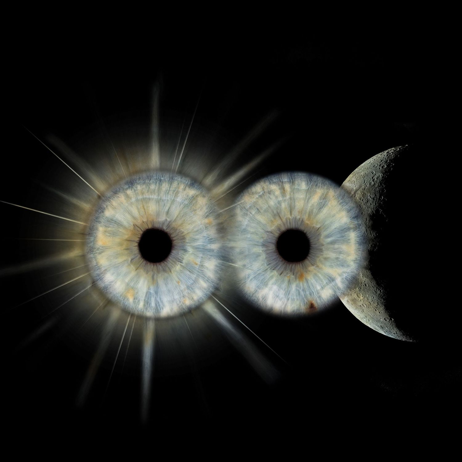 Two human irises side by side resembling solar eclipse and moon on black background.
