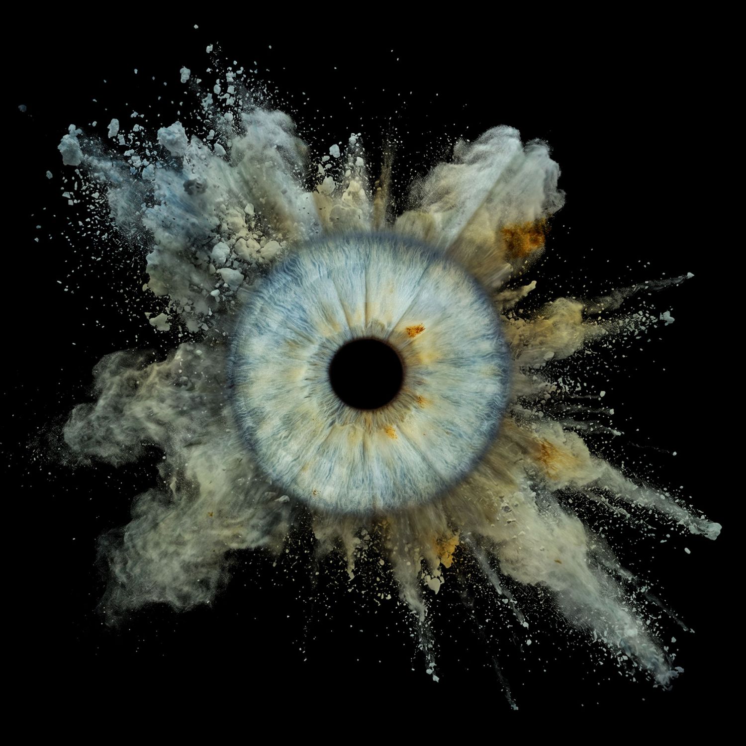 Dramatic macro photo of a blue human eye with beige powder explosion on black background.