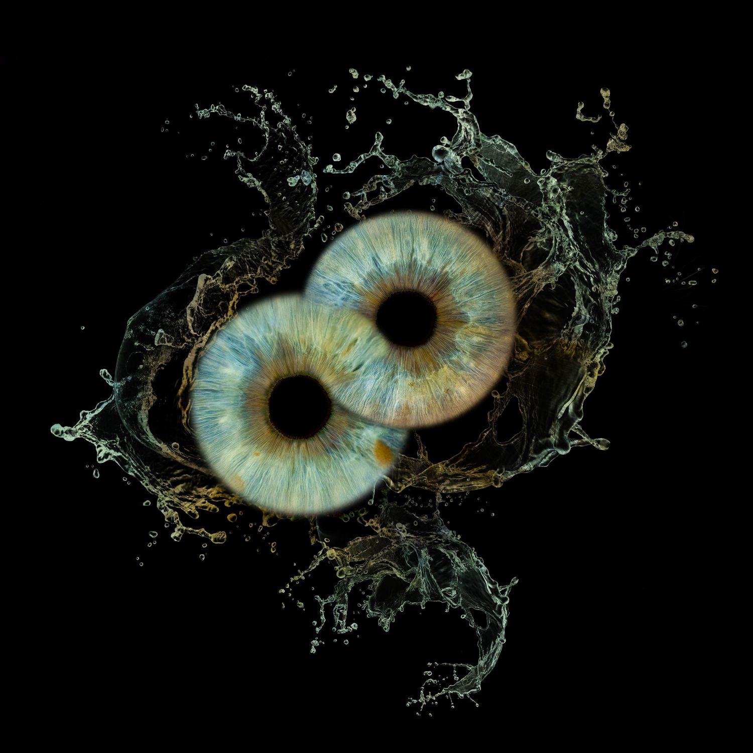 Two human irises with blue-green eyes surrounded by dramatic water splashes on a black background.