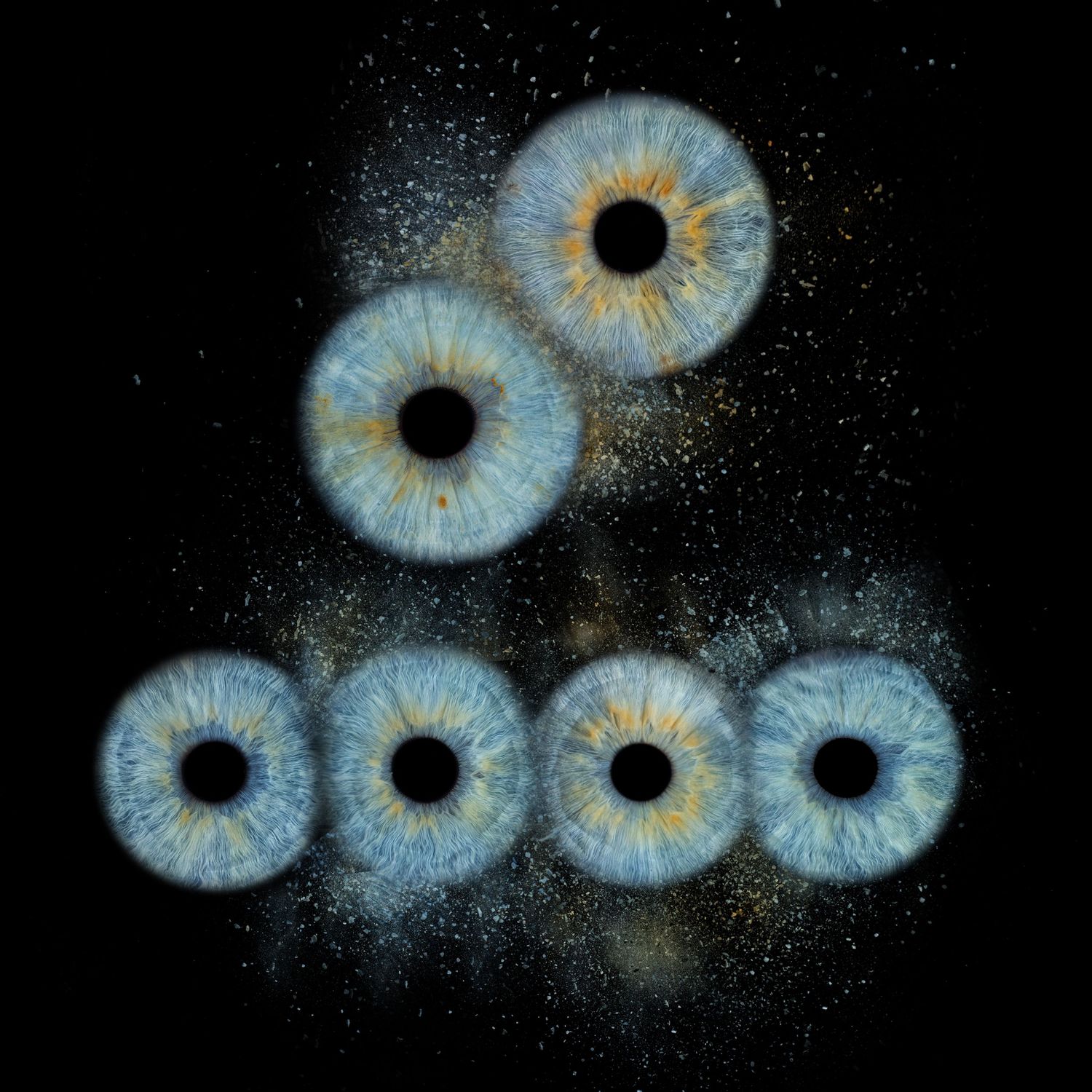 Seven blue human irises arranged in a triangular pattern against a dark starry background with golden light reflections.
