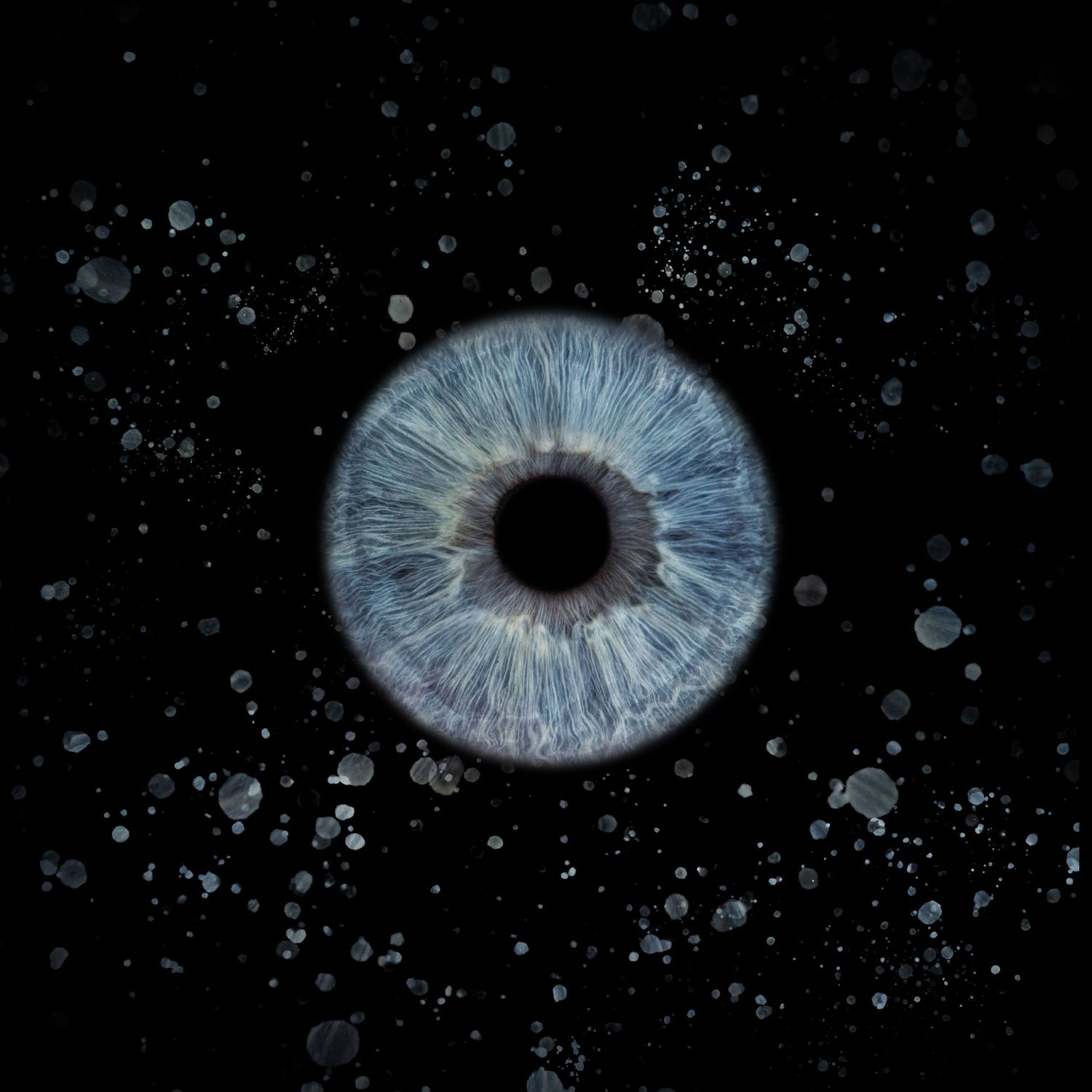 Close-up macro photo of a blue human iris with water droplets on dark background.