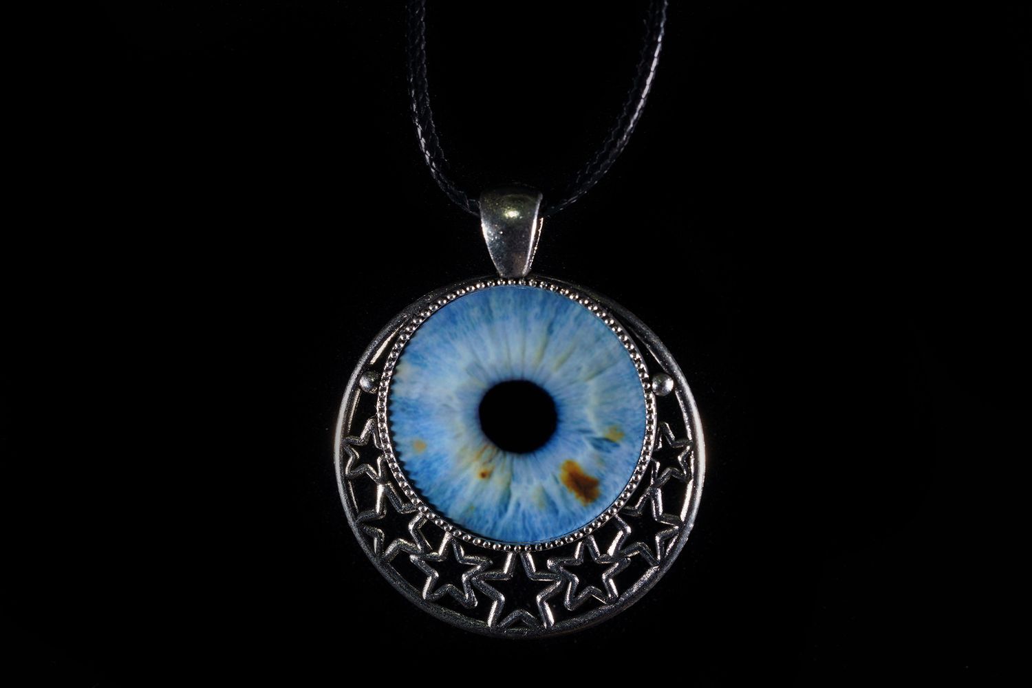 A silver pendant necklace featuring a detailed blue glass eye design with an intricate metal framework around it.