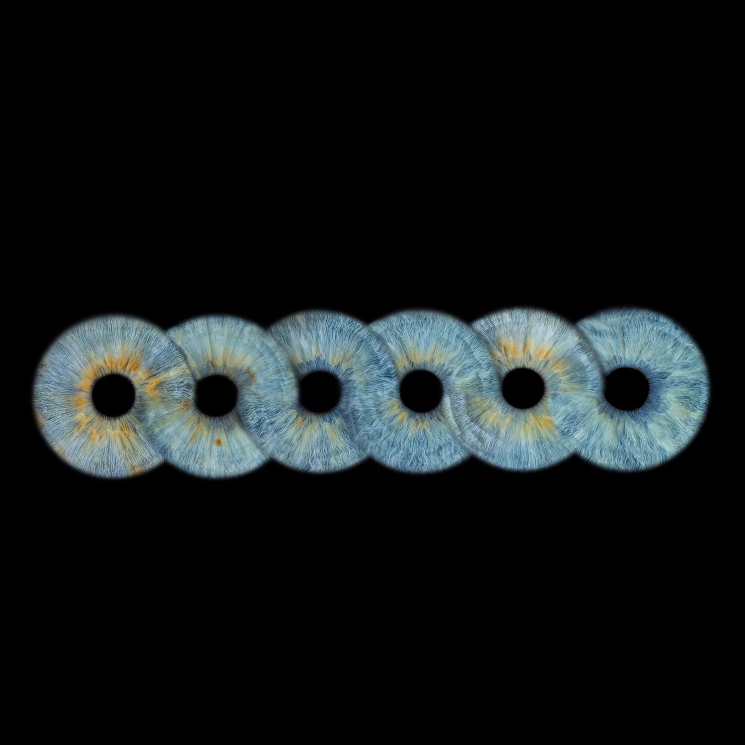 Six blue human irises with golden centers arranged in a row on a black background.