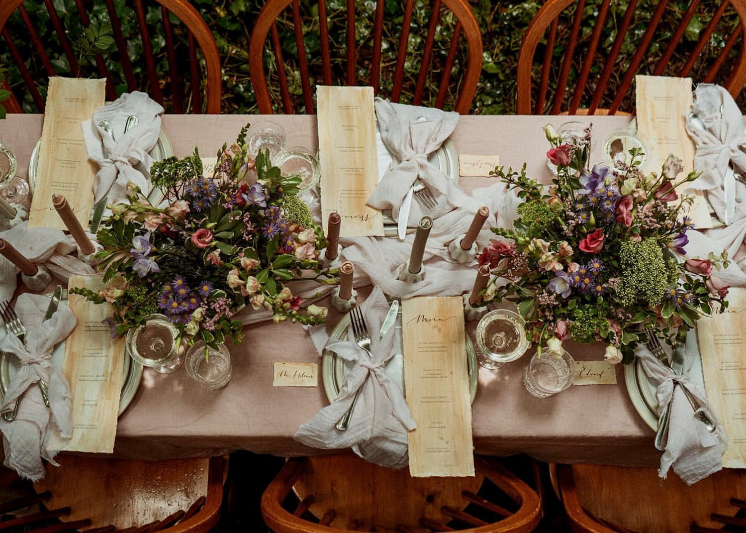 Elegant rustic wedding table centerpiece with lush wildflower arrangements and draped ribbon place settings.